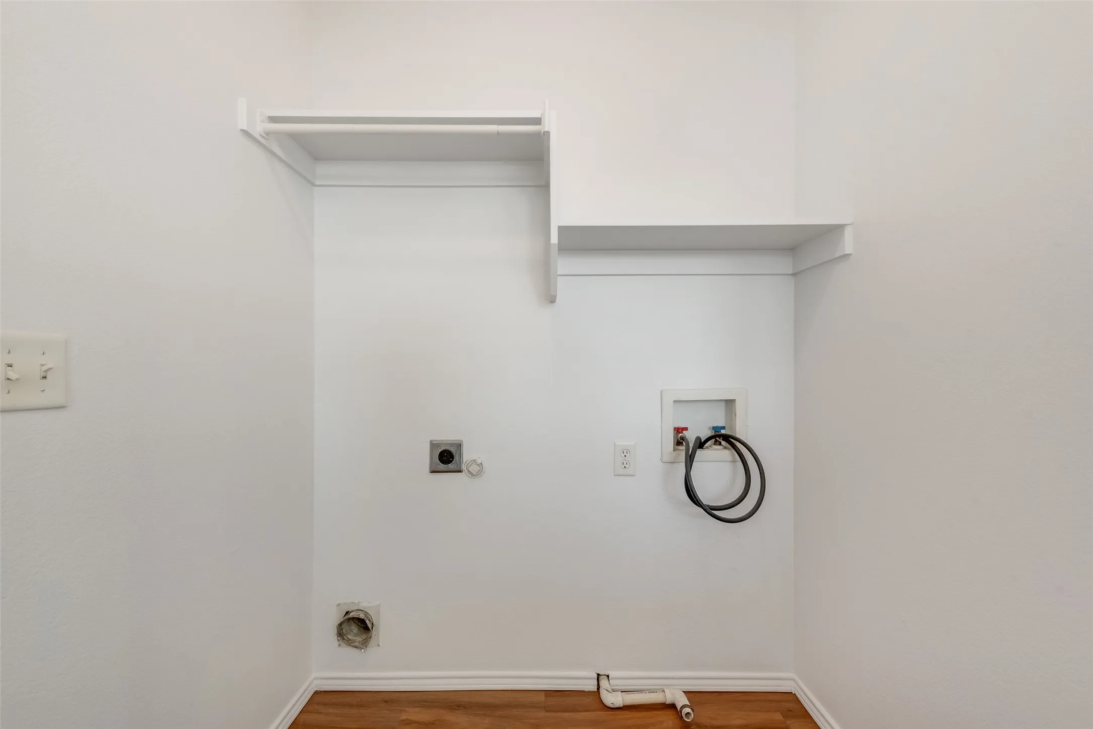 Laundry area with wood-finish flooring, white walls, and built-in shelving