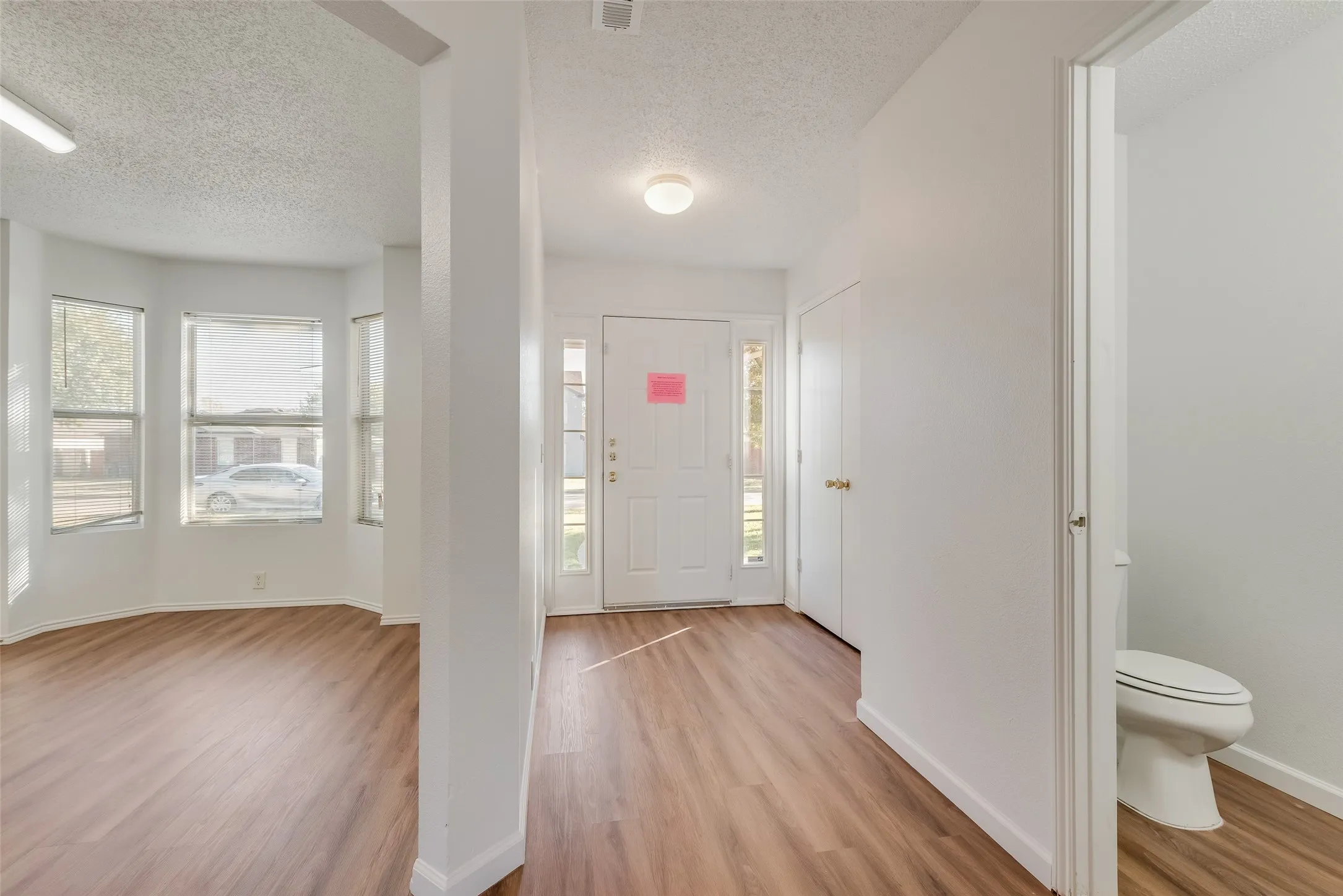 Entryway featuring wood-finish flooring, white walls, and a front door with sidelights