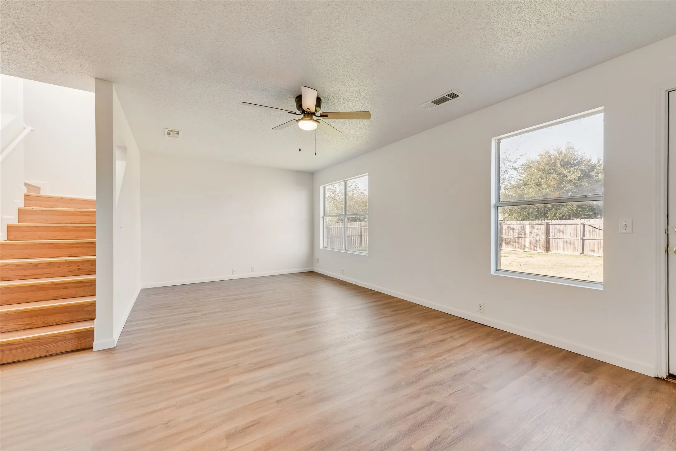 Wood-finish flooring, white painted walls, and a ceiling fan