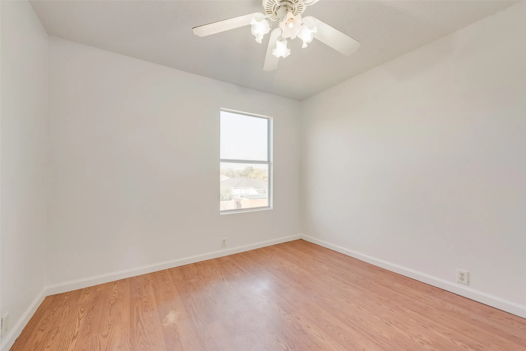 Wood-finish flooring, single window, overhead ceiling fan with lighting, white walls, and white trim