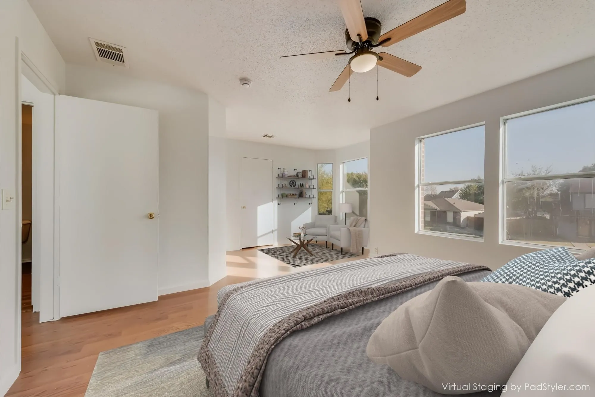 Wood-finish flooring throughout, bright white walls, multiple large windows, and a ceiling fan with integrated lighting