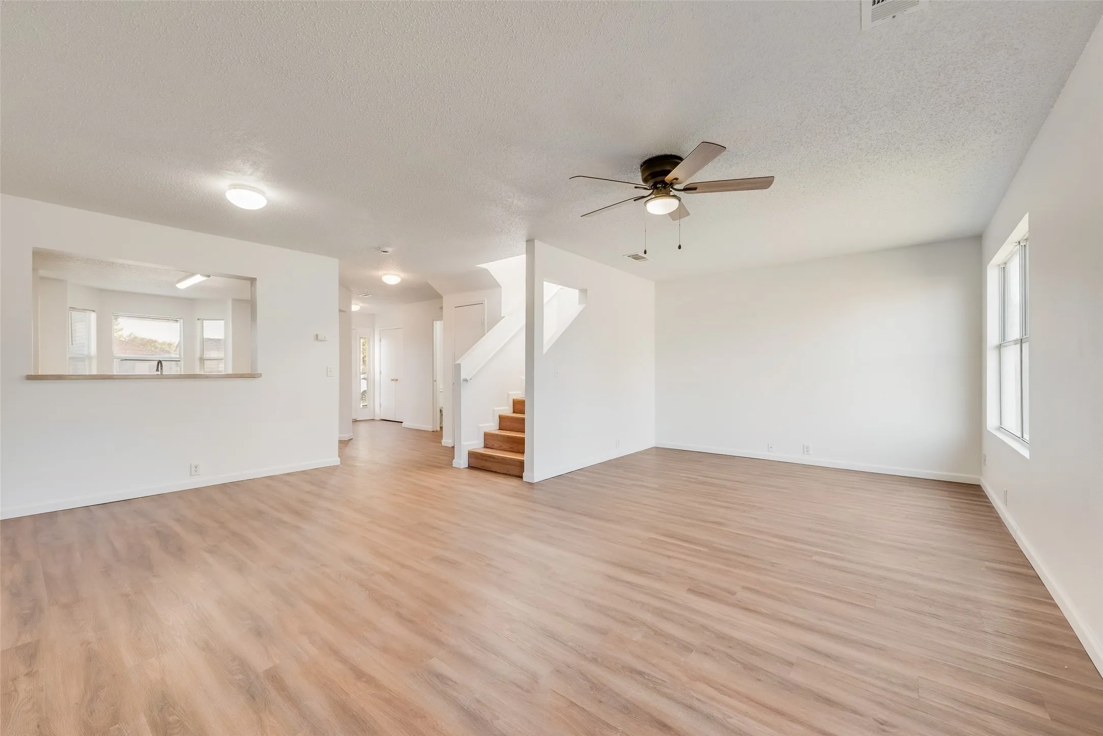 Expansive interior with wood-finish flooring, a ceiling fan, and a large window