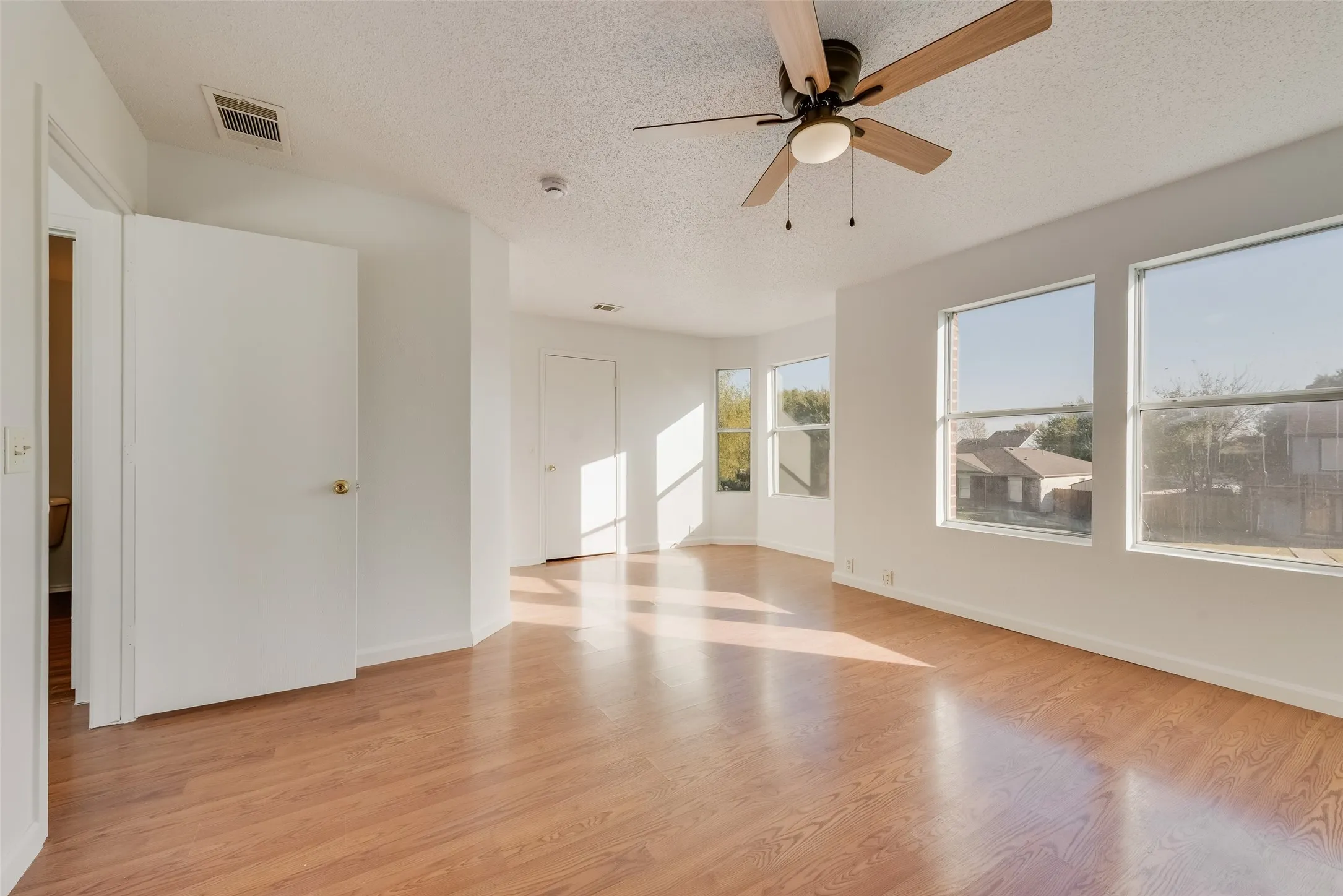 Wood-finish flooring throughout, complemented by a ceiling fan with integrated lighting