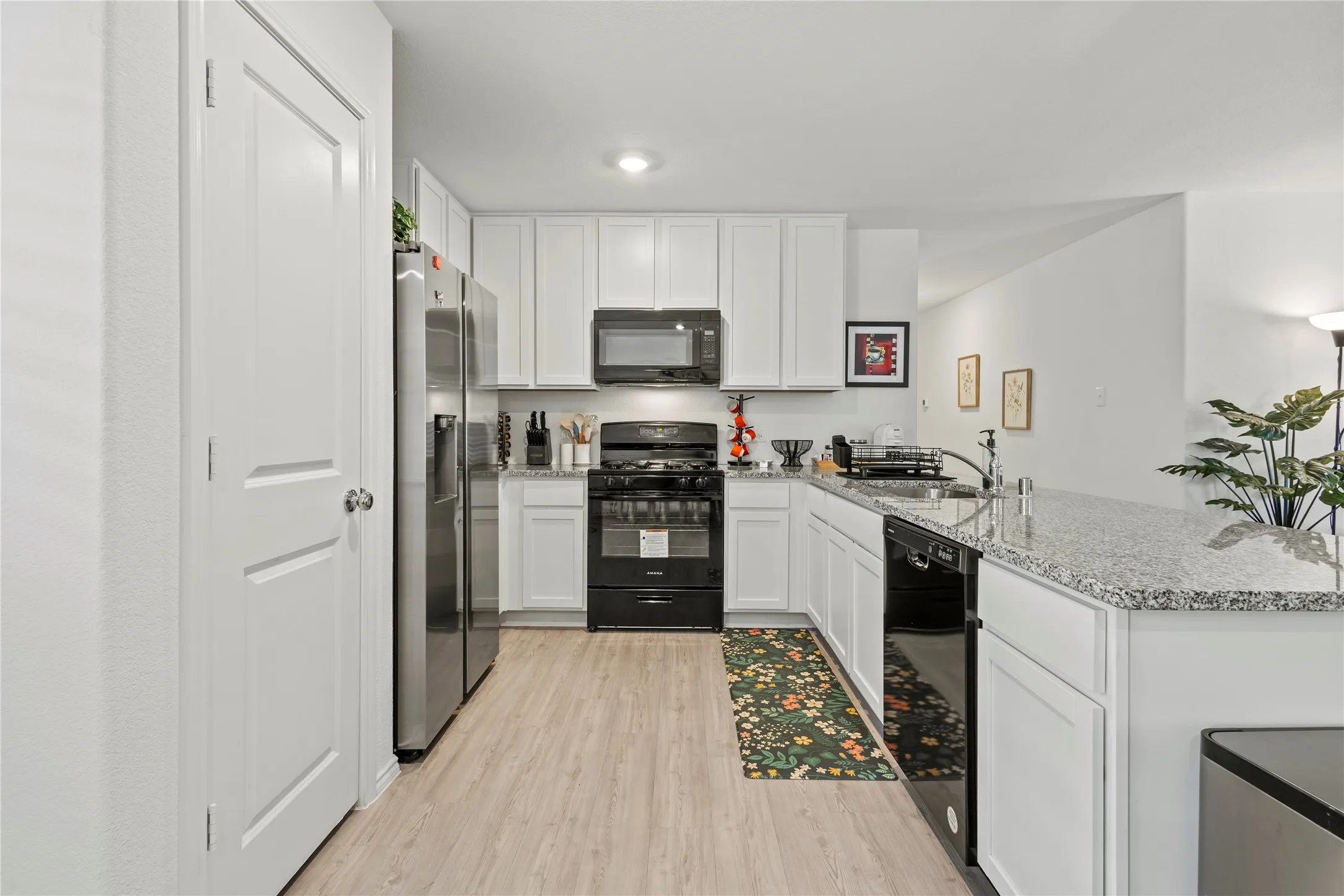 Kitchen featuring white cabinetry, stainless steel appliances, granite countertops, wood-finish flooring, and recessed lighting