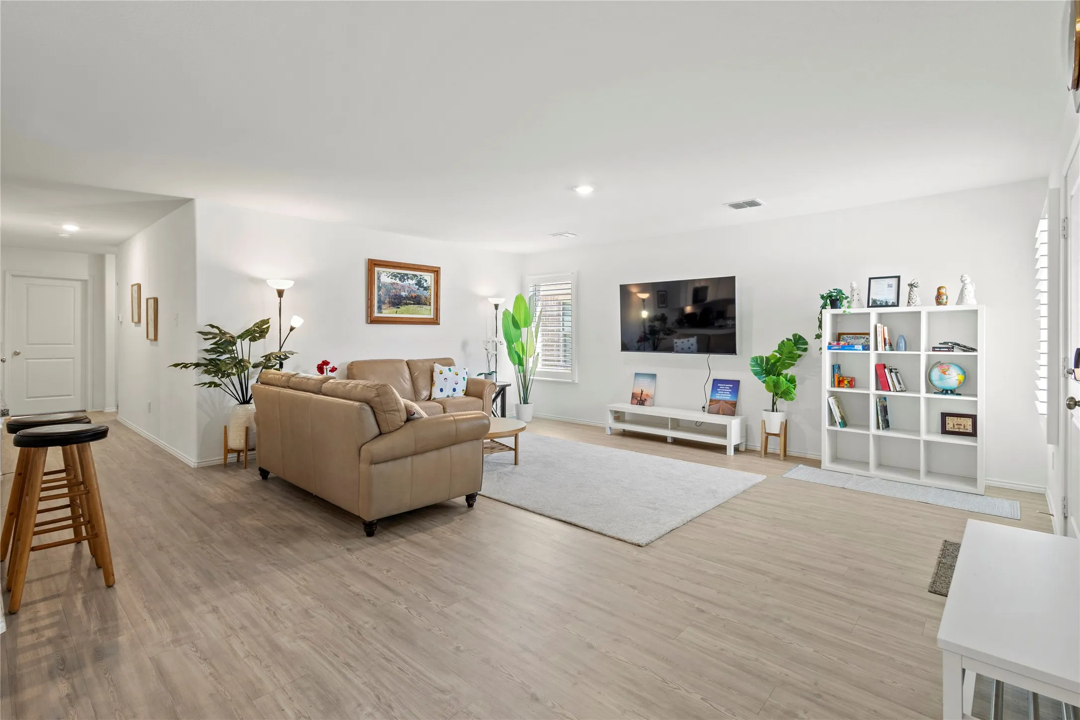 Spacious interior with light wood-finish flooring, white walls, recessed lighting, and white plantation shutters