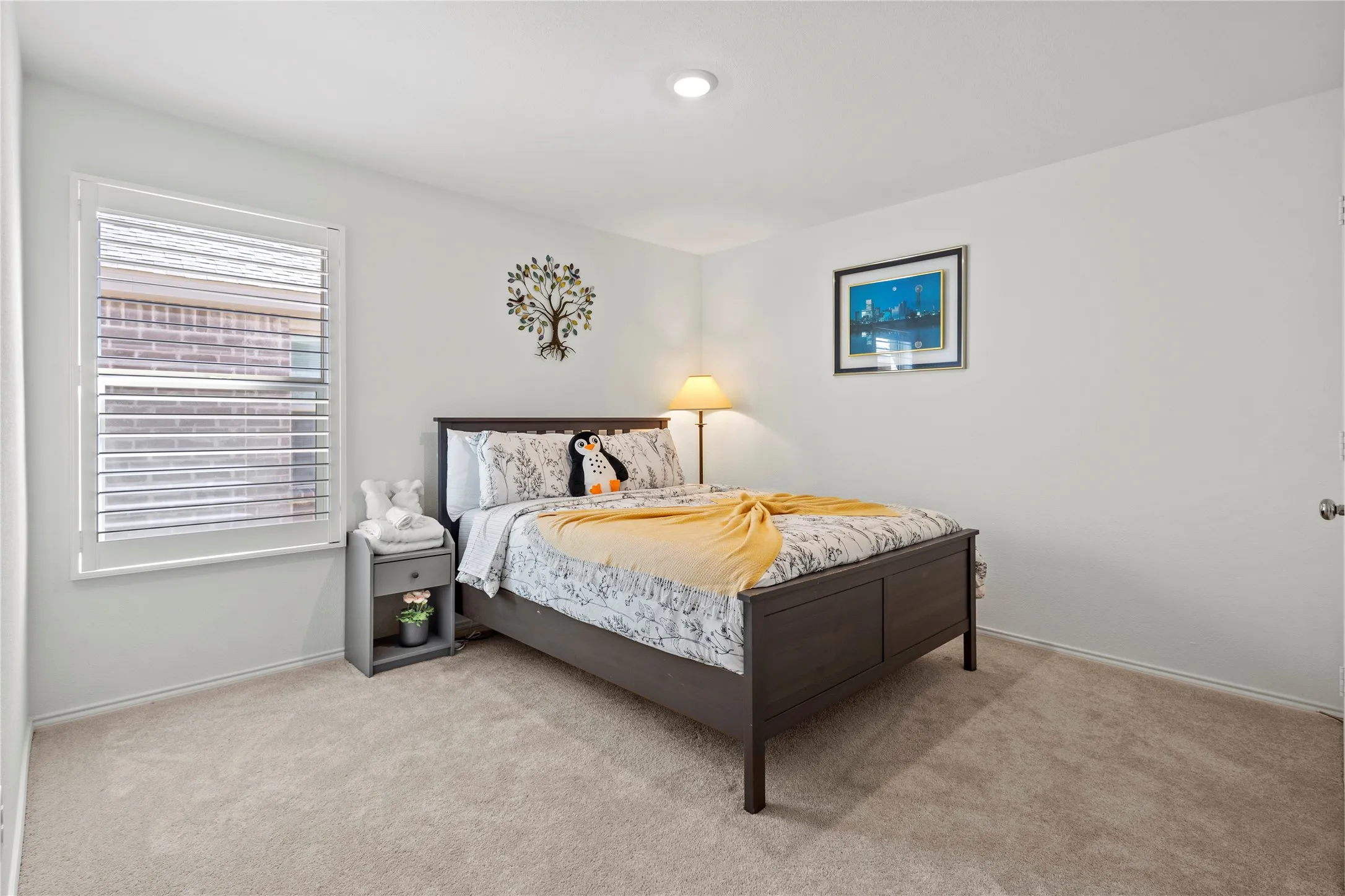 Recessed ceiling lighting, white walls, carpeted flooring, and a window with white louvered shutters