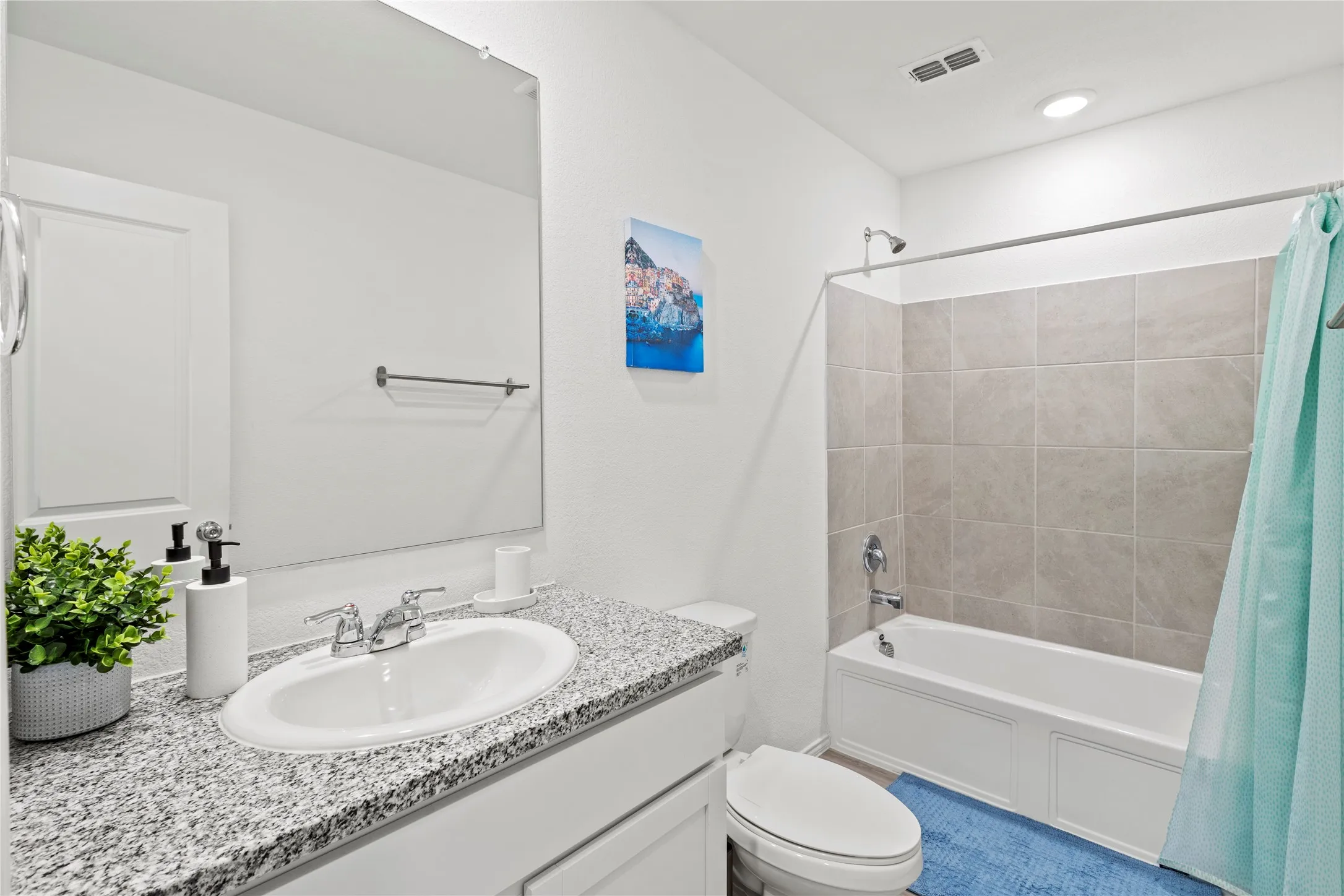 Bathroom featuring a single vanity with stone-finish countertop, under-mount sink, and chrome fixtures