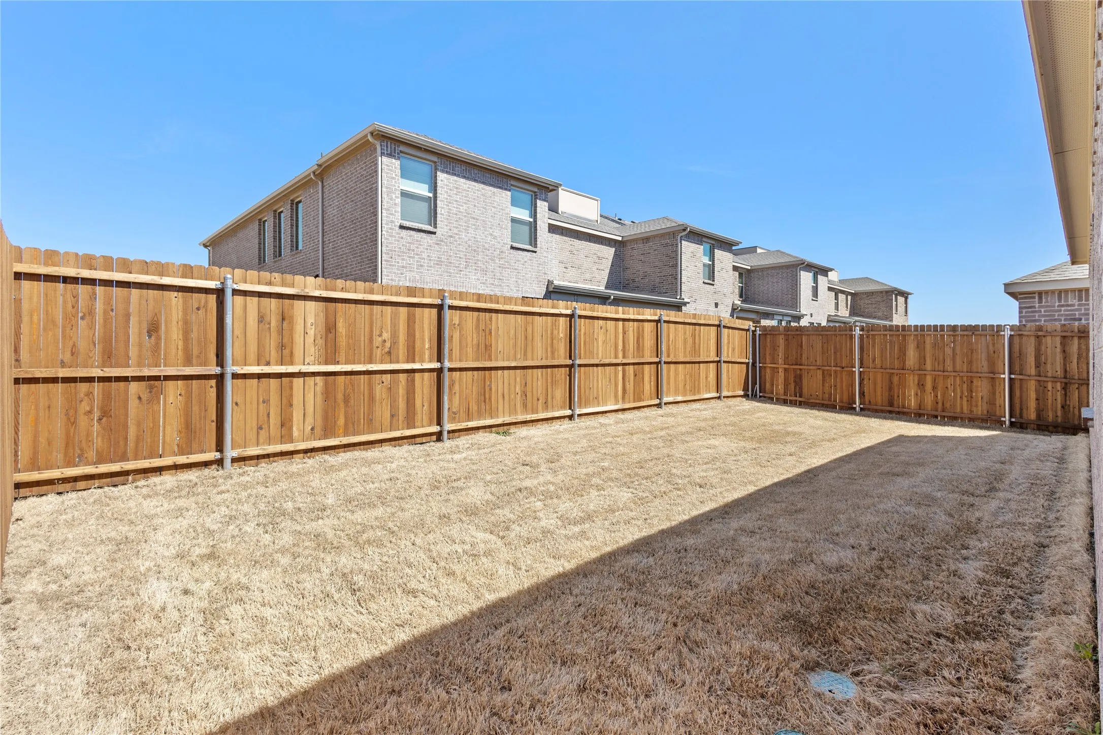 Expansive fenced backyard featuring wood panel fencing and an open lawn area