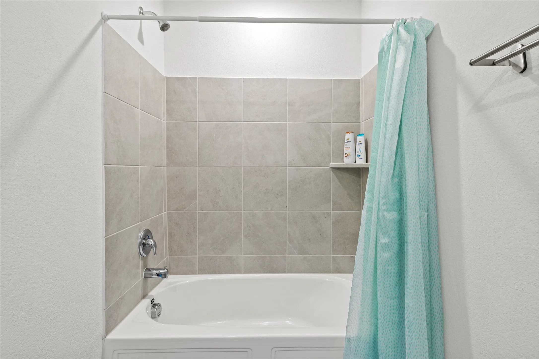 Tub and shower combination featuring neutral-toned tile surround and chrome fixtures