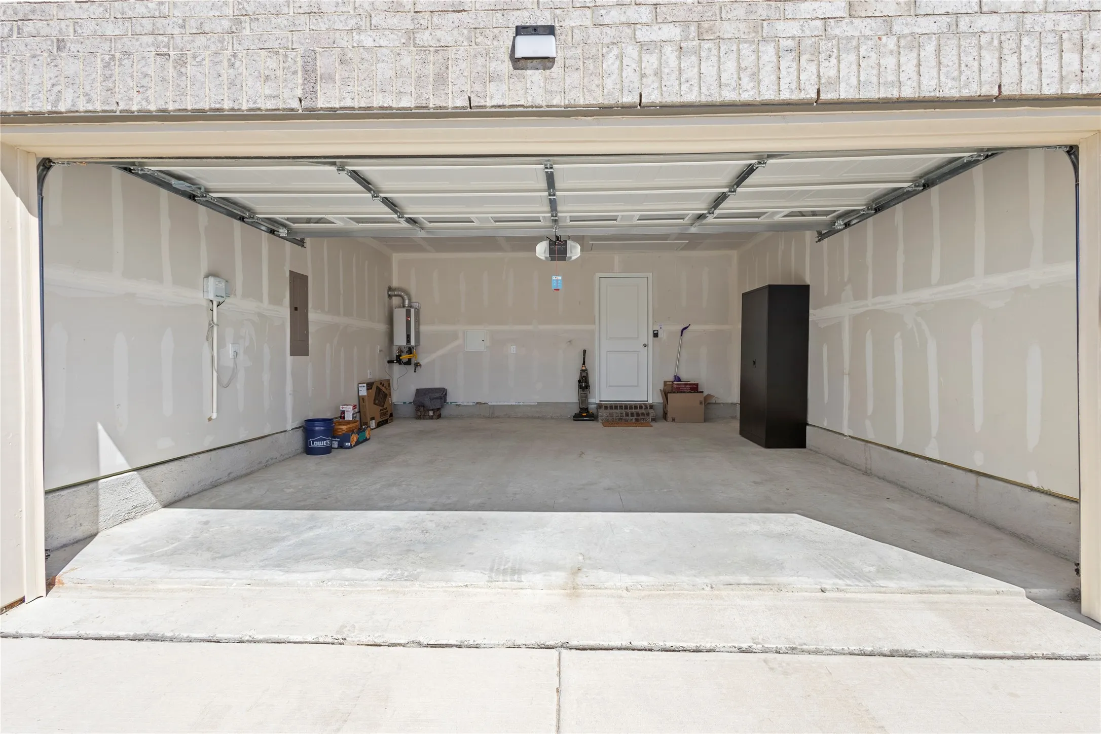 Spacious two-car garage with concrete flooring, automatic garage door opener, and a side entry door