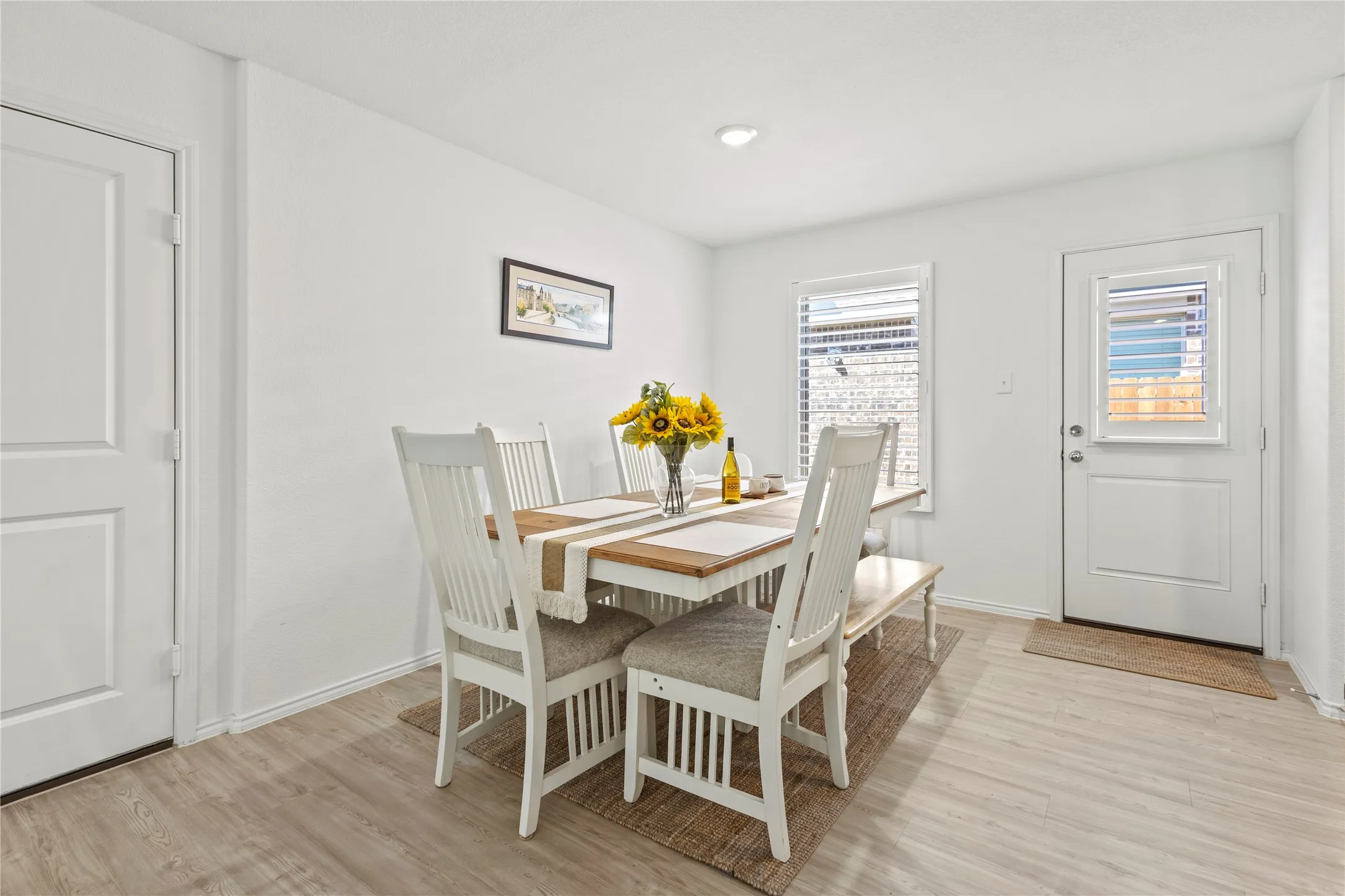 Light-toned wood-finish flooring, white walls, white trim, recessed lighting, and a white paneled door
