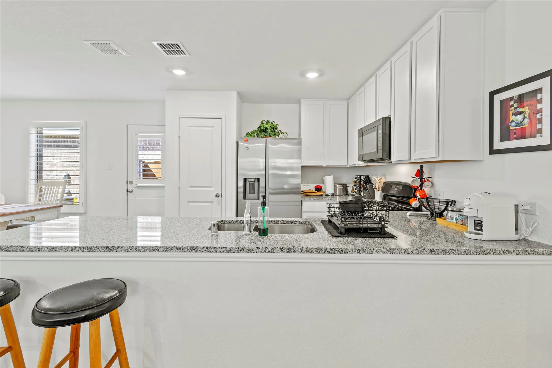 Kitchen featuring white cabinetry, granite countertops, stainless steel appliances, and a double basin sink
