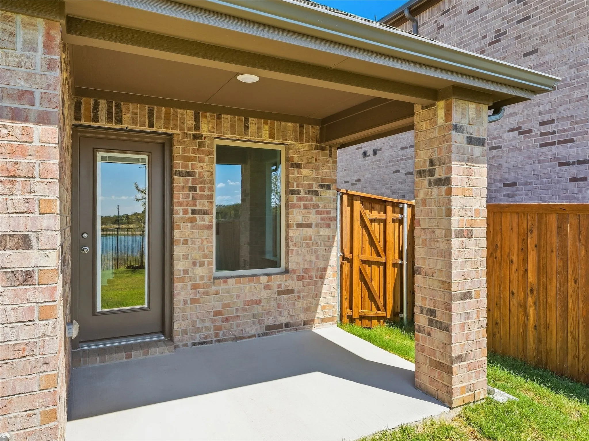 Covered patio with brick columns, brick exterior, and a wood privacy fence