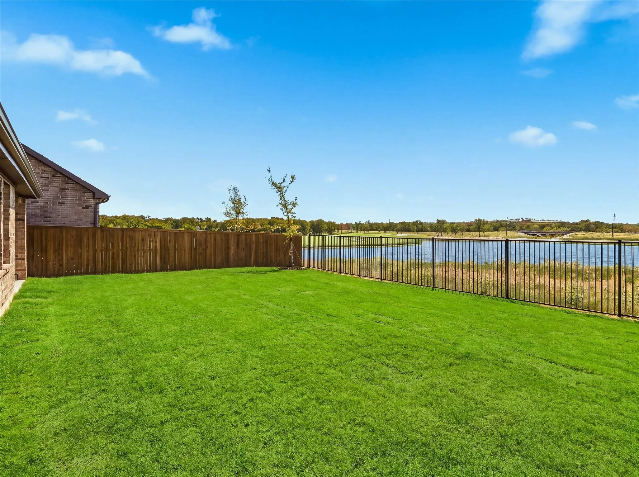 lake and Golf view with a full privacy fence and an additional black metal perimeter fence