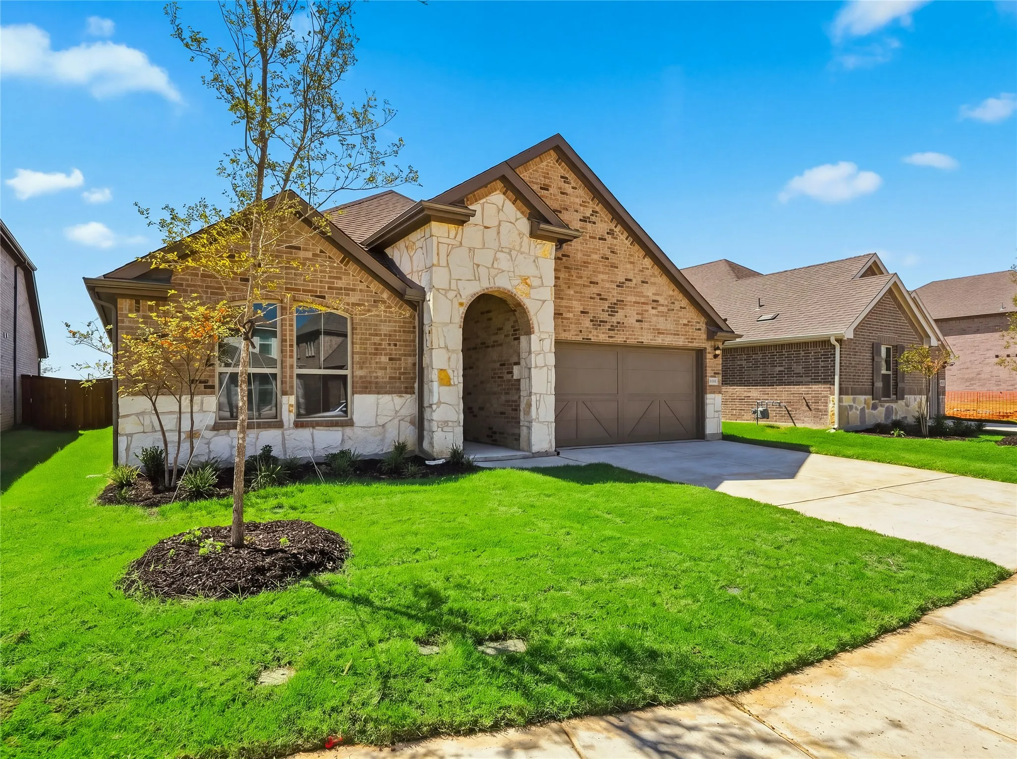 Brick and stone facade with an arched entry, fully landscaped