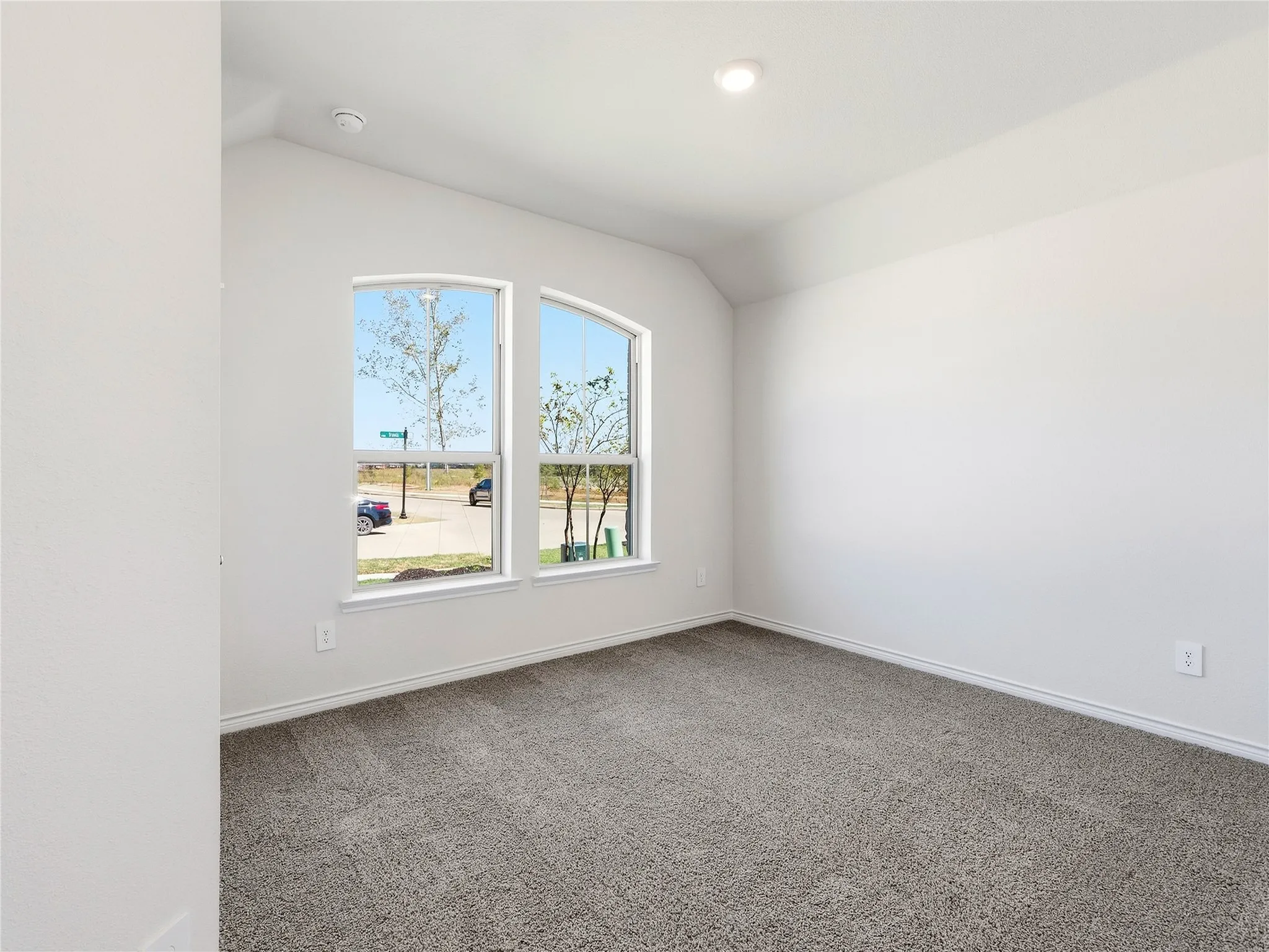 Arched windows, neutral wall color, recessed lighting, and carpet flooring
