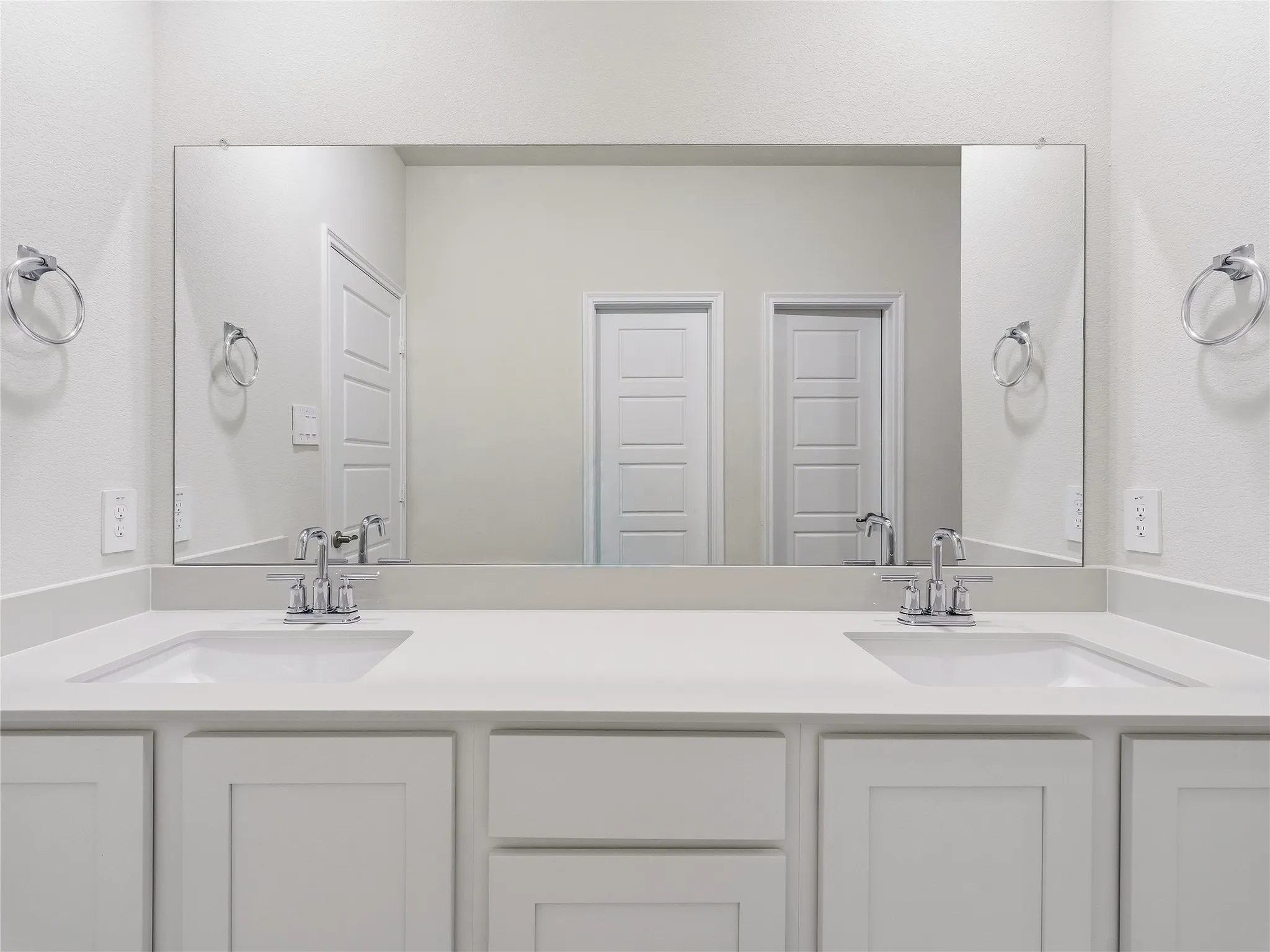 Dual vanity with white cabinetry, inset panel doors, undermount sinks, and chrome faucets