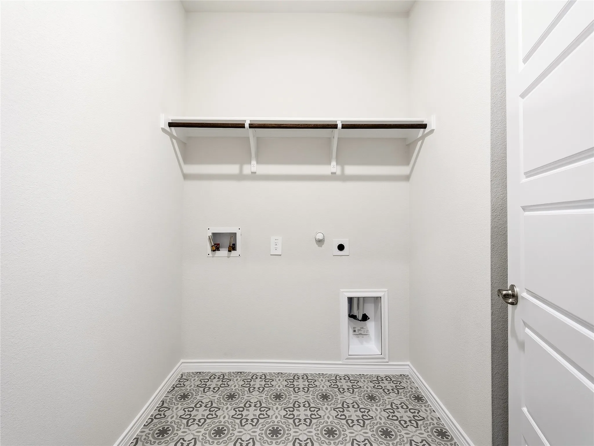 Laundry area featuring a durable patterned tile floor, built-in shelving, and a modern paneled door