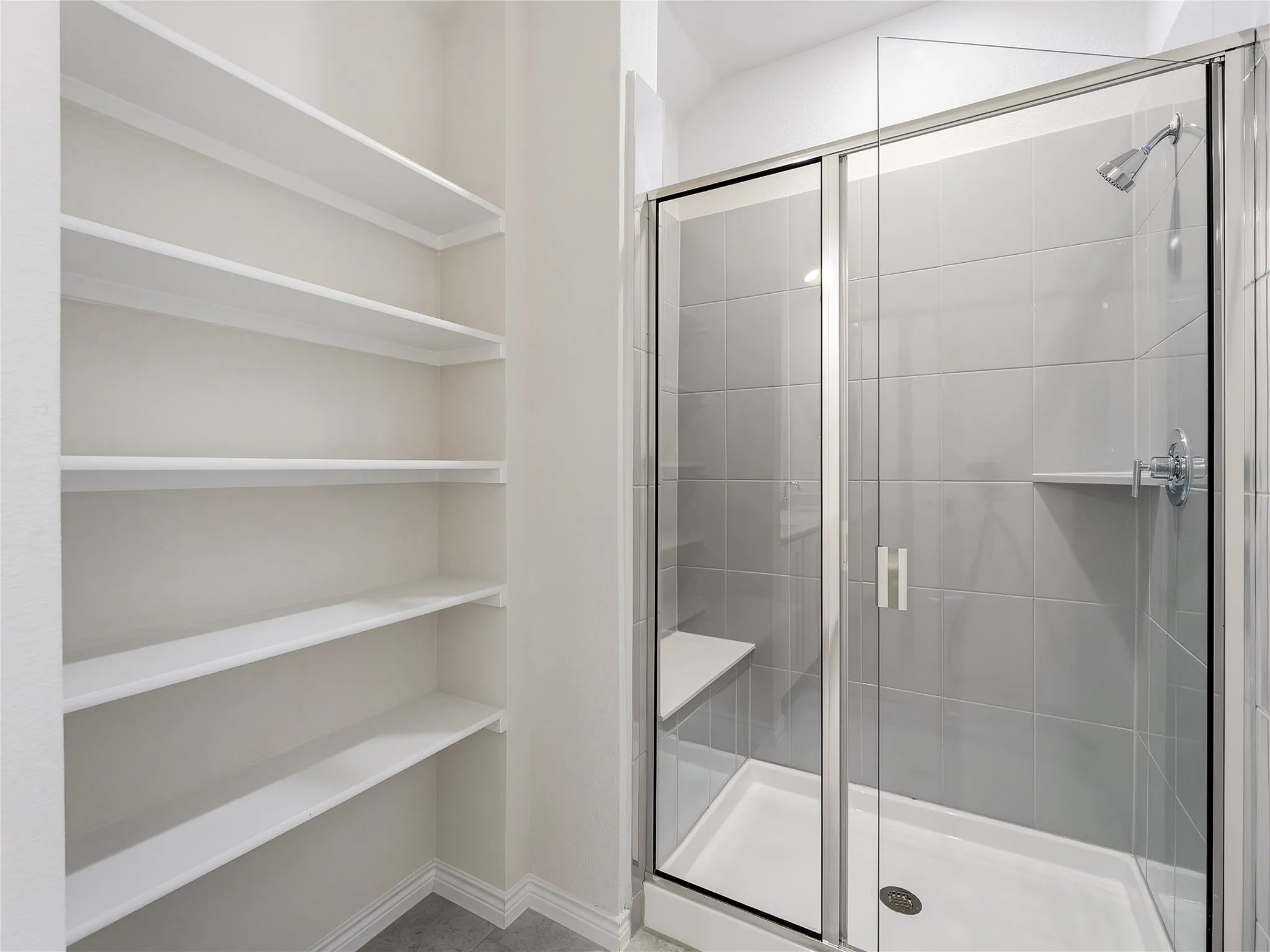 Walk-in glass shower with built-in bench and practical shelving.
