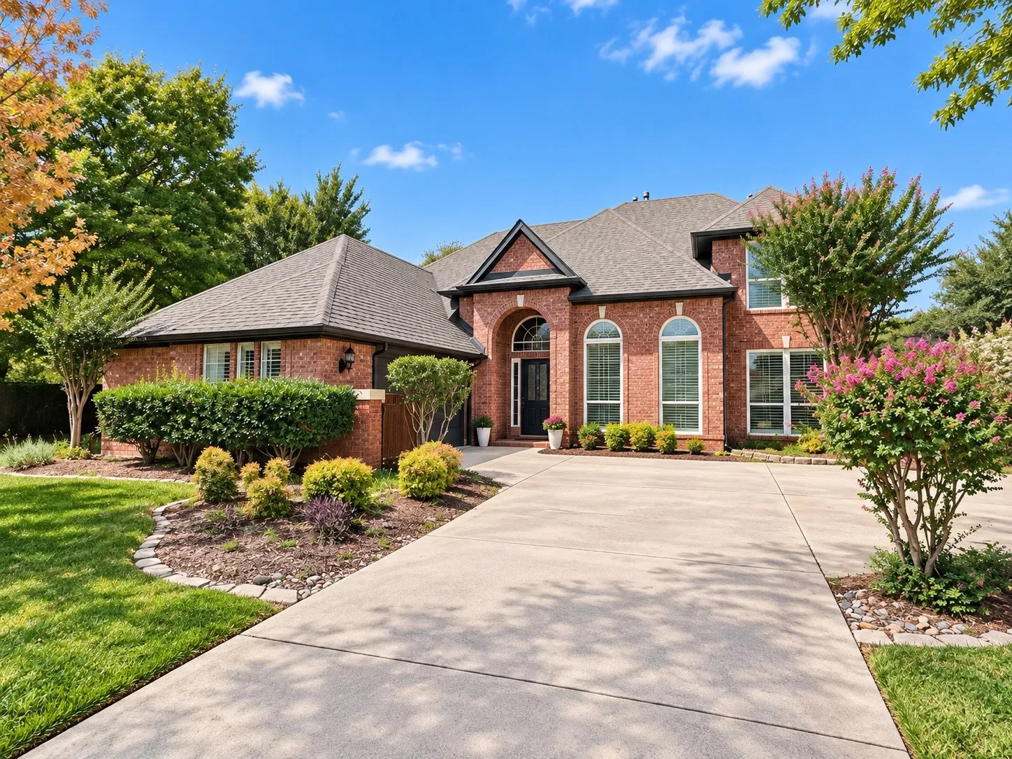 Brick exterior with arched windows, a covered entry, and an expansive driveway