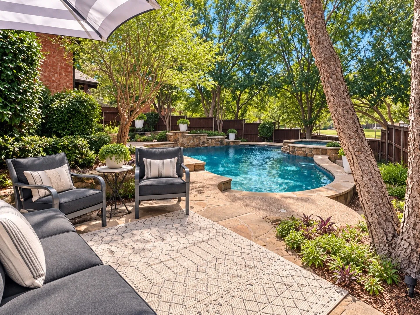 Curved swimming pool with an integrated spa, surrounded by stone coping and hardscaping