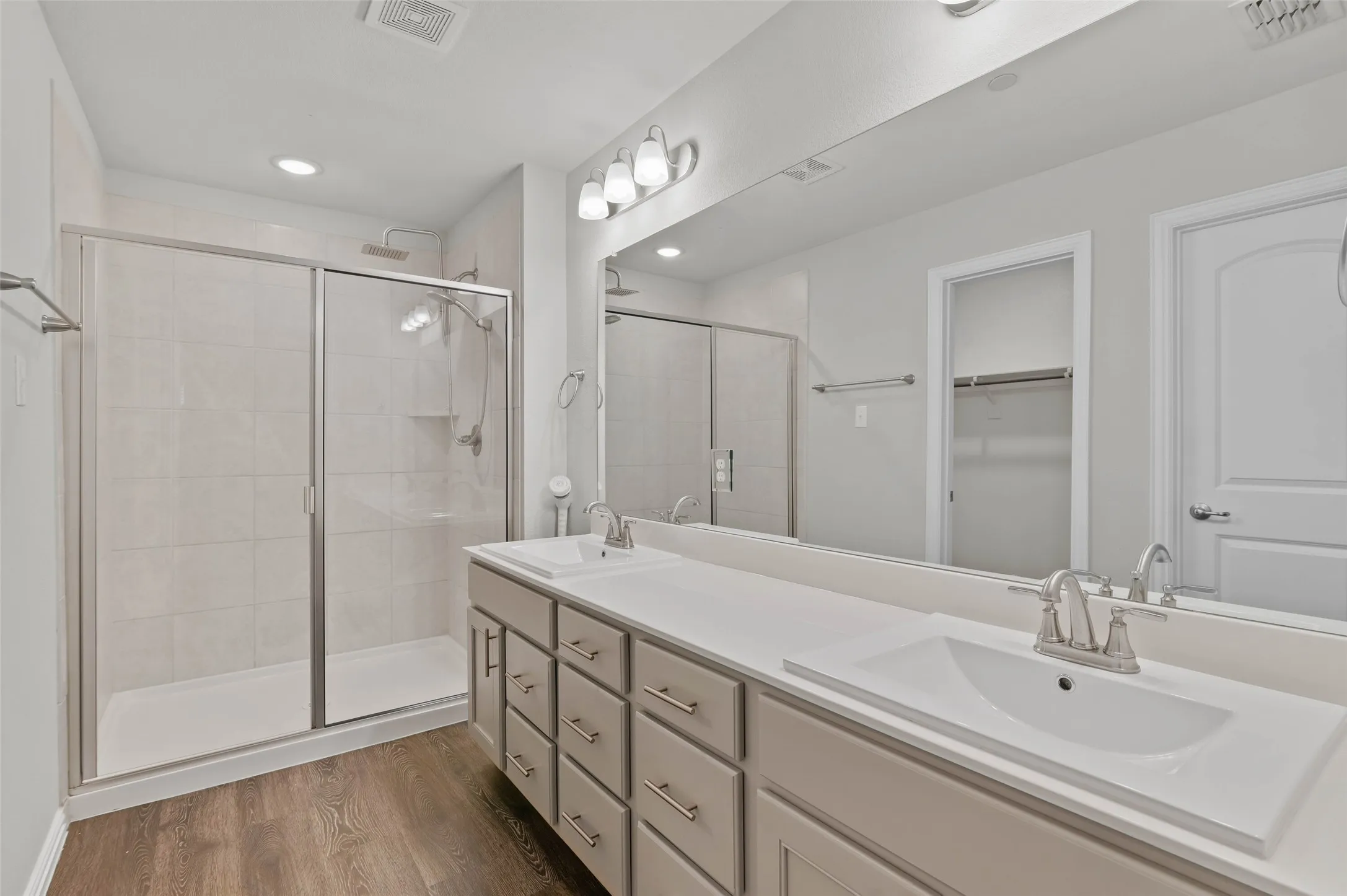Primary ensuite bathroom with dual vanities, walk in shower and second walk in closet