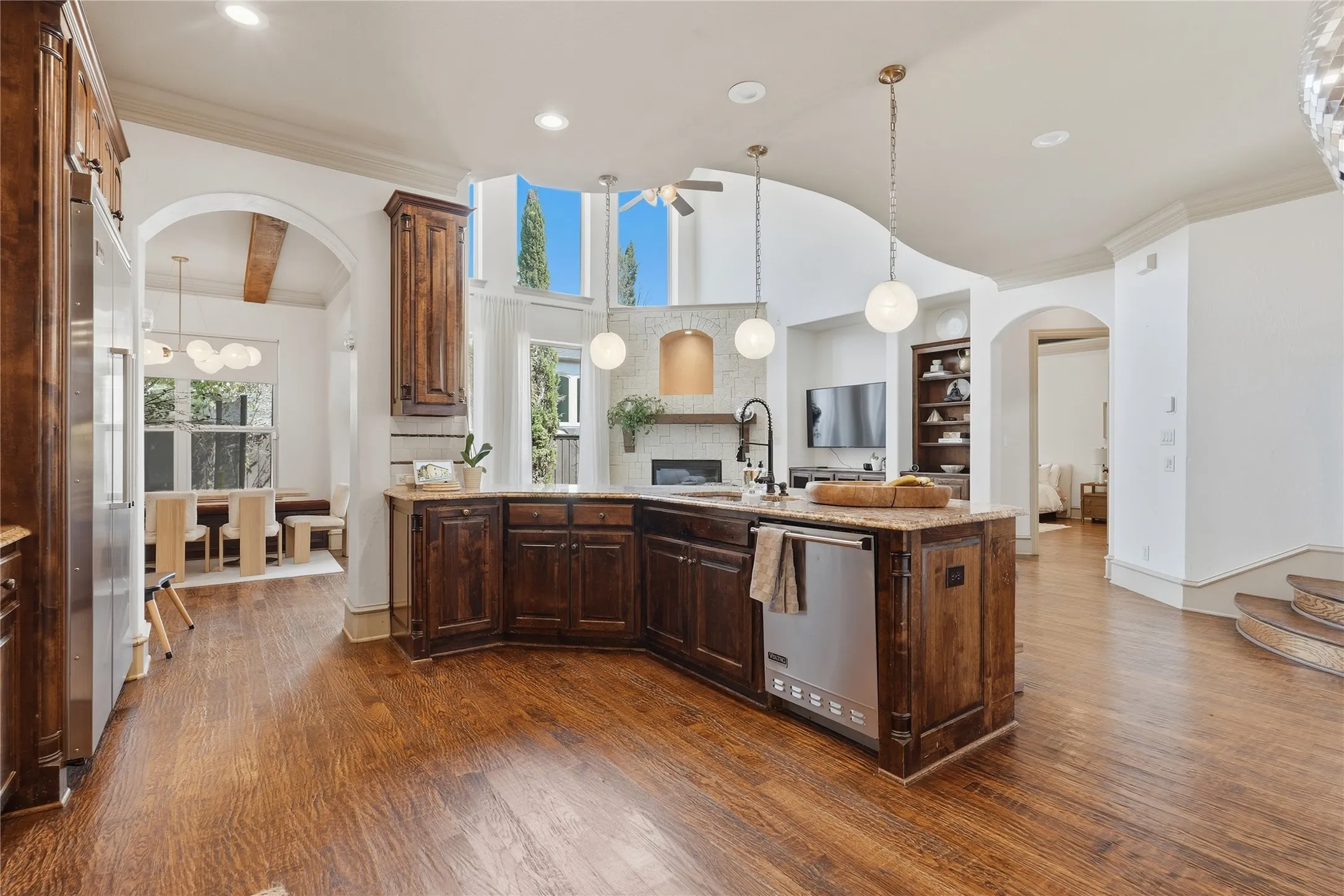 Kitchen featuring a central island, wood-finish flooring, custom cabinetry, stainless steel appliances, and an arched entryway