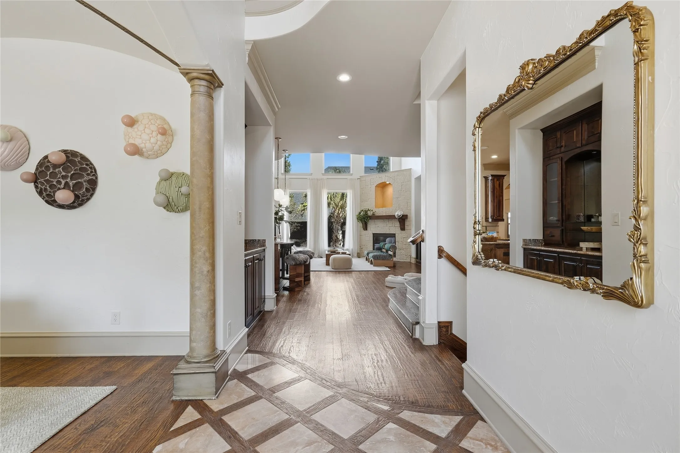 Expansive entry featuring hardwood flooring with tile inlay, architectural archways, and a decorative column