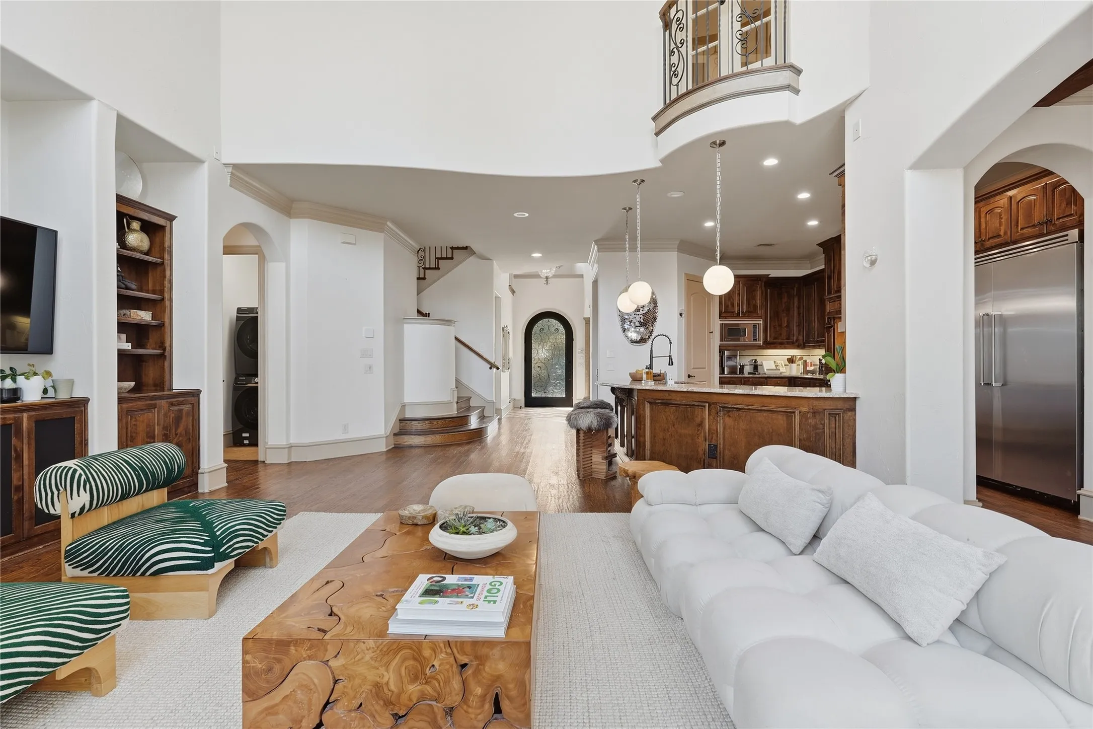 Two-story living area with hardwood flooring, integrated shelving, and arched entryways