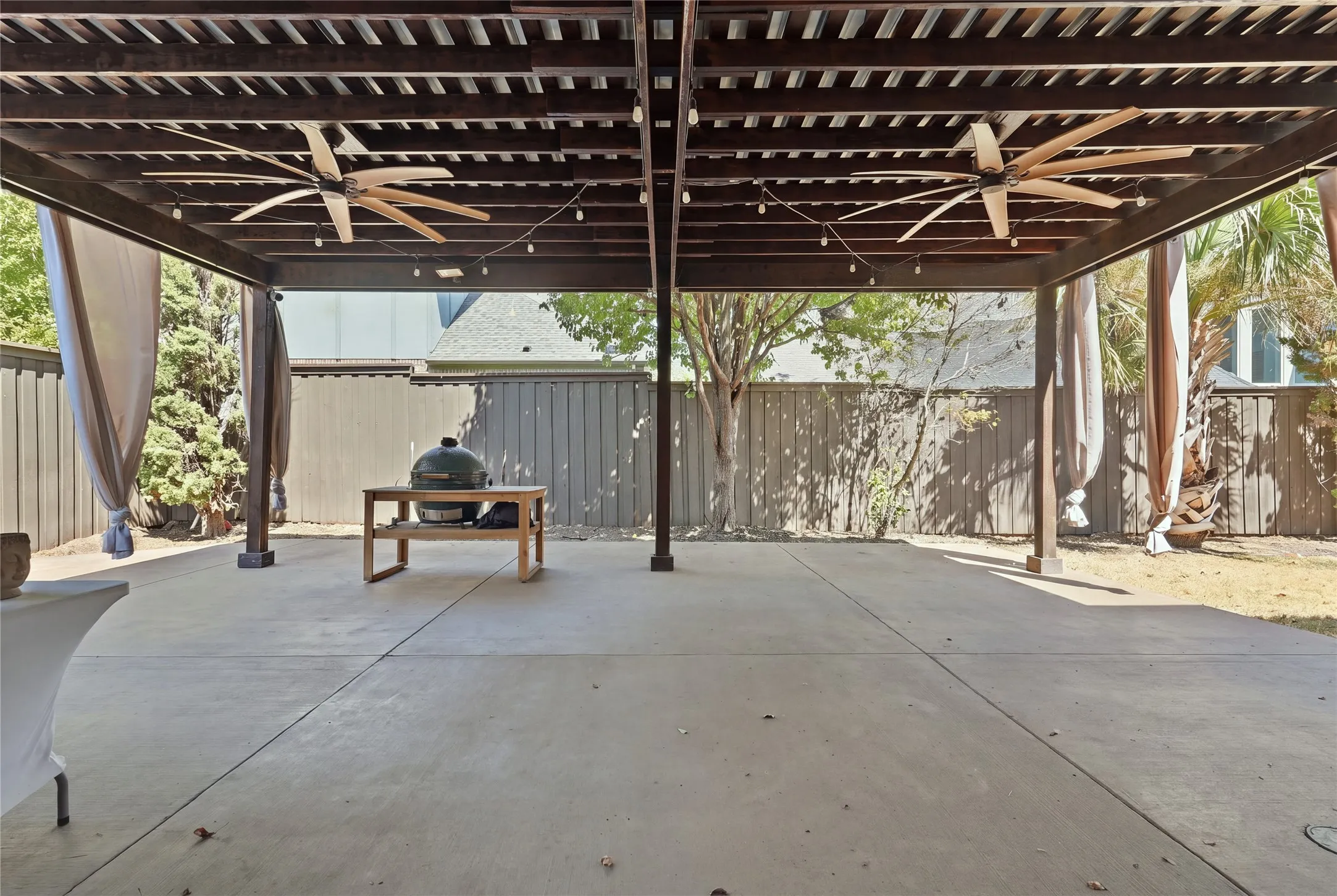 Expansive covered patio featuring a wood pergola, dual ceiling fans, and string lighting