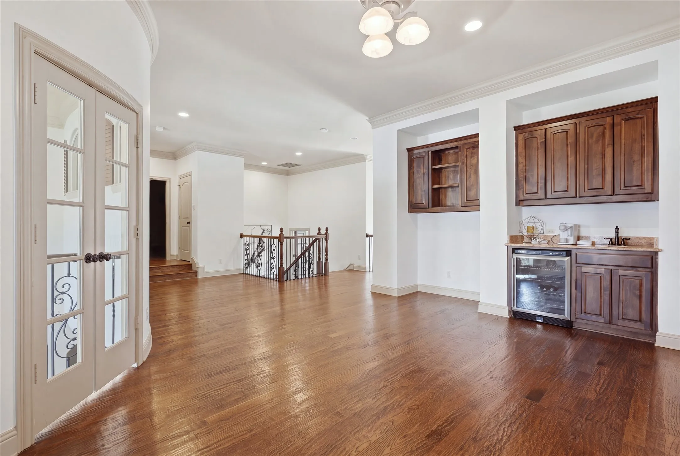 Hardwood flooring, wet bar with built-in beverage cooler, recessed lighting, crown molding, and French doors