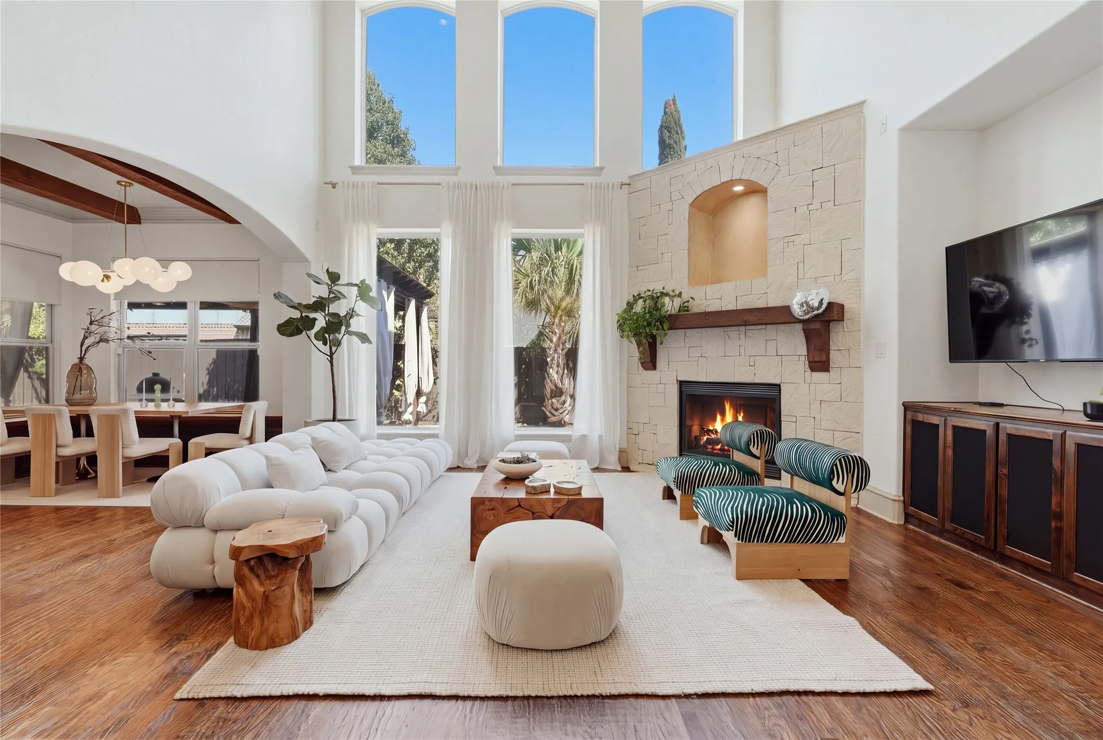 Two-story living room featuring a stone-clad fireplace with a wood mantel