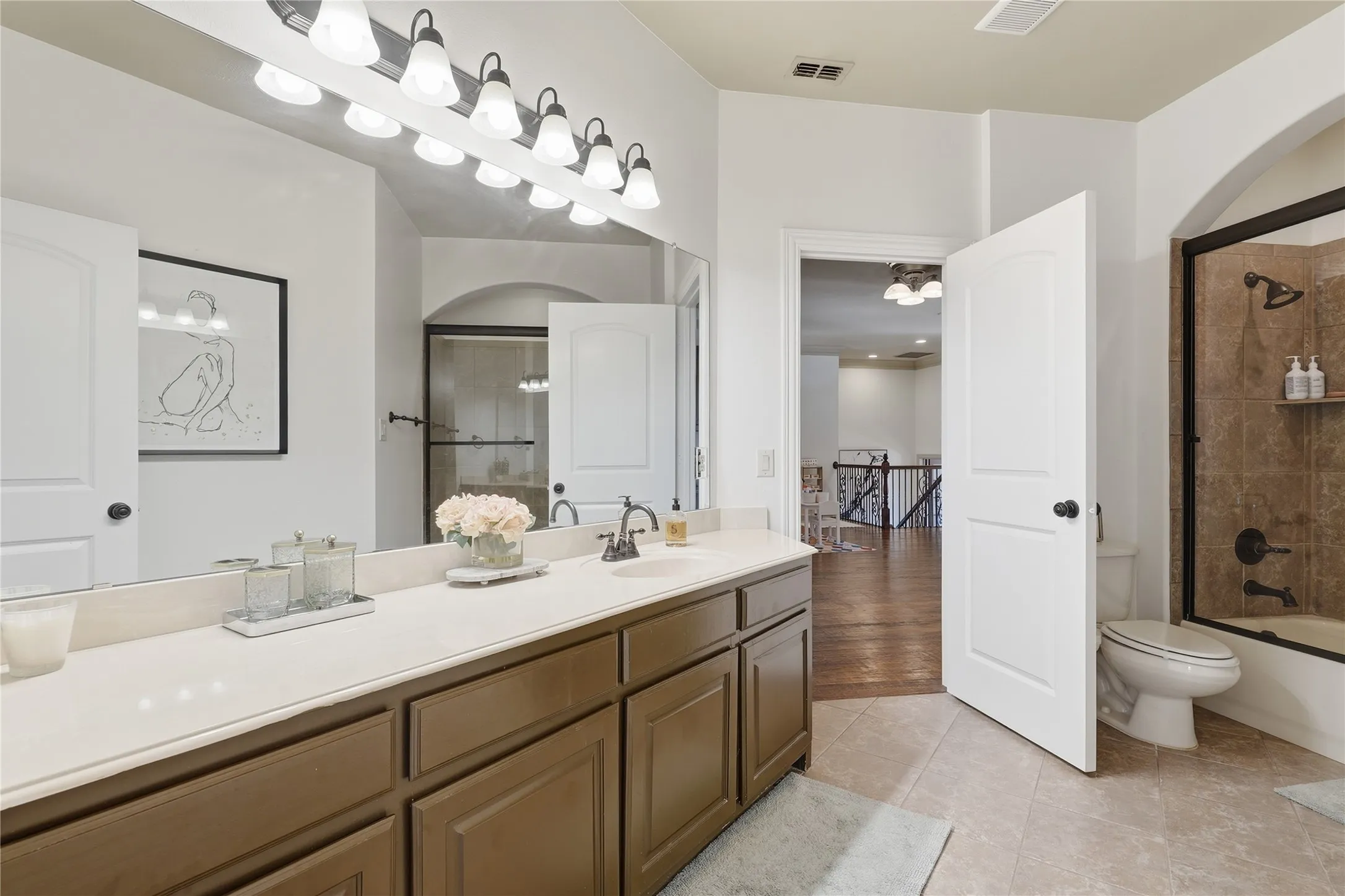 Expansive vanity with double sinks, light-toned countertop, and brown cabinetry