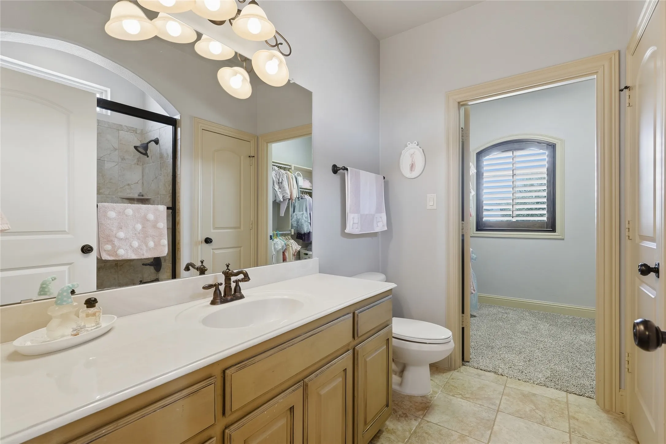 Bathroom featuring a single vanity with an integrated sink, bronze-finish faucet, and light-toned cabinetry