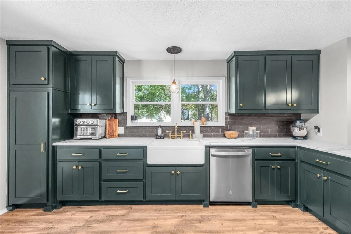 Kitchen featuring new cabinetry, white marbled quartz countertops, a farmhouse sink, stainless steel dishwasher, and wood-finish flooring