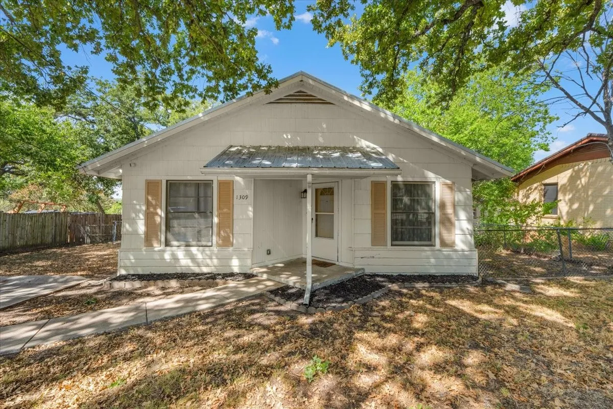White siding exterior with a pitched roof, front entry porch, and a concrete walk path