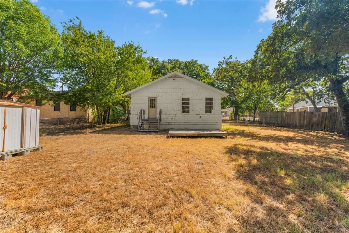 Expansive backyard featuring a detached storage shed, mature trees, and privacy fencing