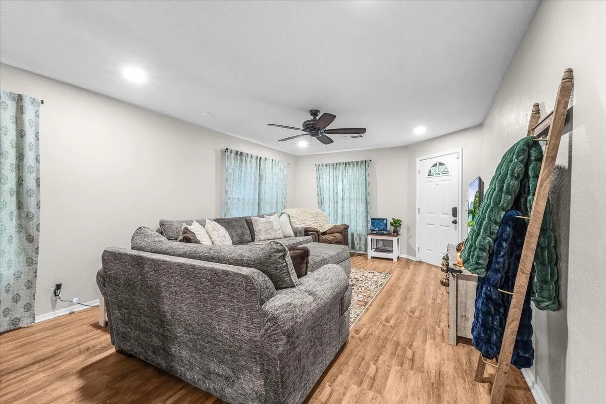 Wood-finish flooring, recessed lighting, ceiling fan, and a front entry door with an arched transom window
