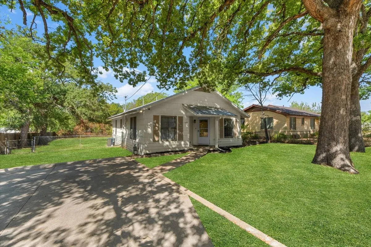 Cute 2 bedroom 1 bath home with a covered front porch, concrete driveway, and mature trees