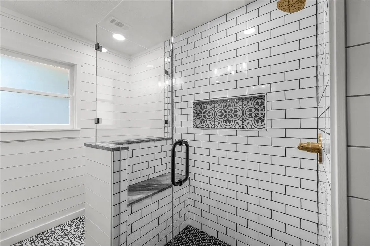 Glass-enclosed shower with white subway tile, a built-in bench, and a decorative tile niche