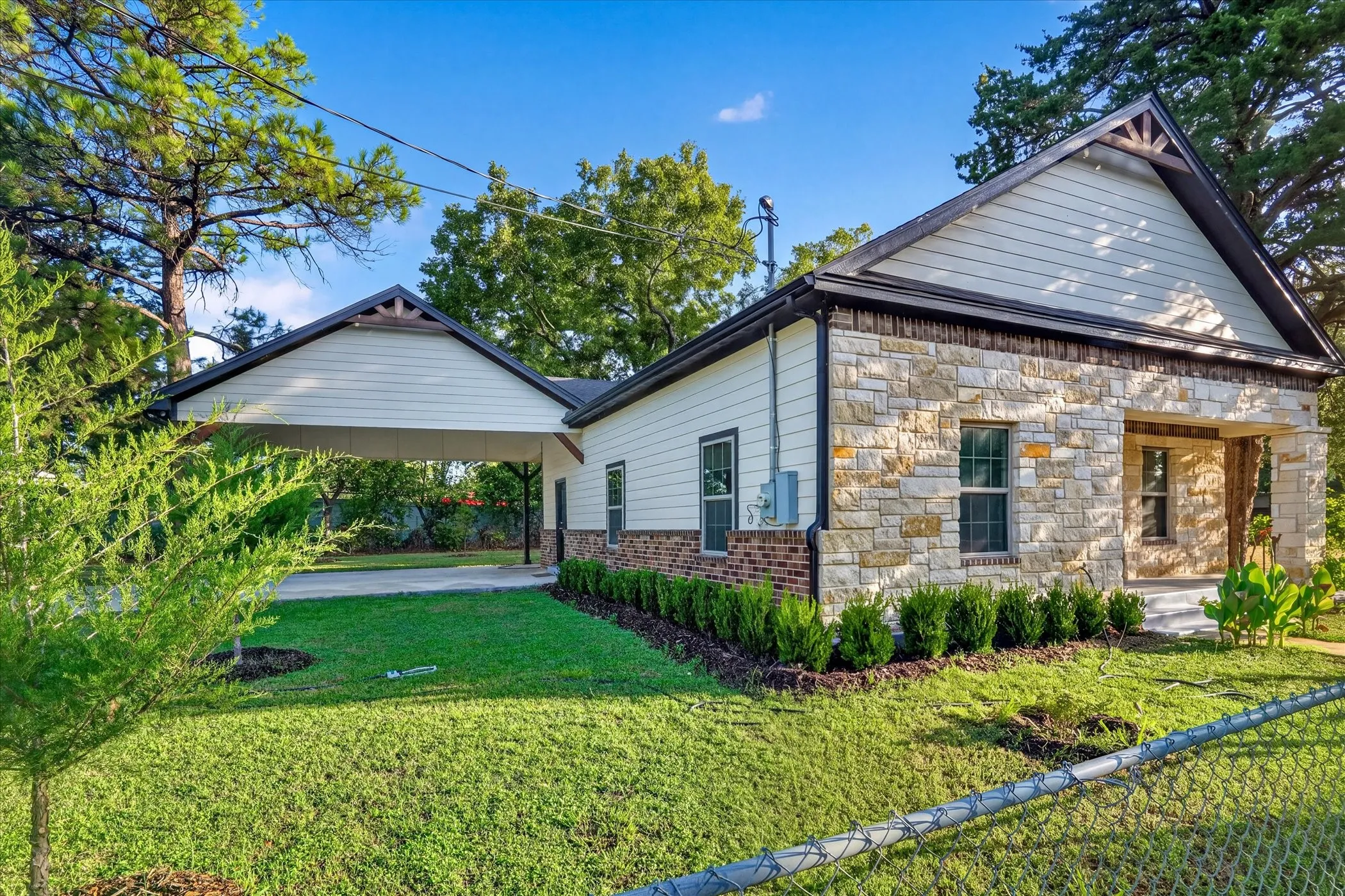 Stone and siding exterior with a covered front porch and a covered carport