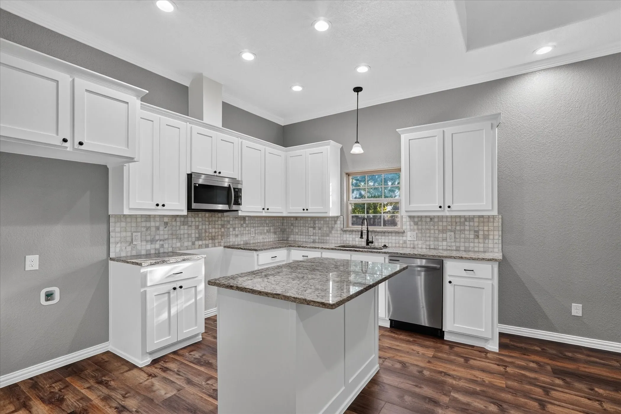 Kitchen featuring white cabinetry, stone countertops, stainless steel appliances, a tile backsplash, and wood-finish flooring