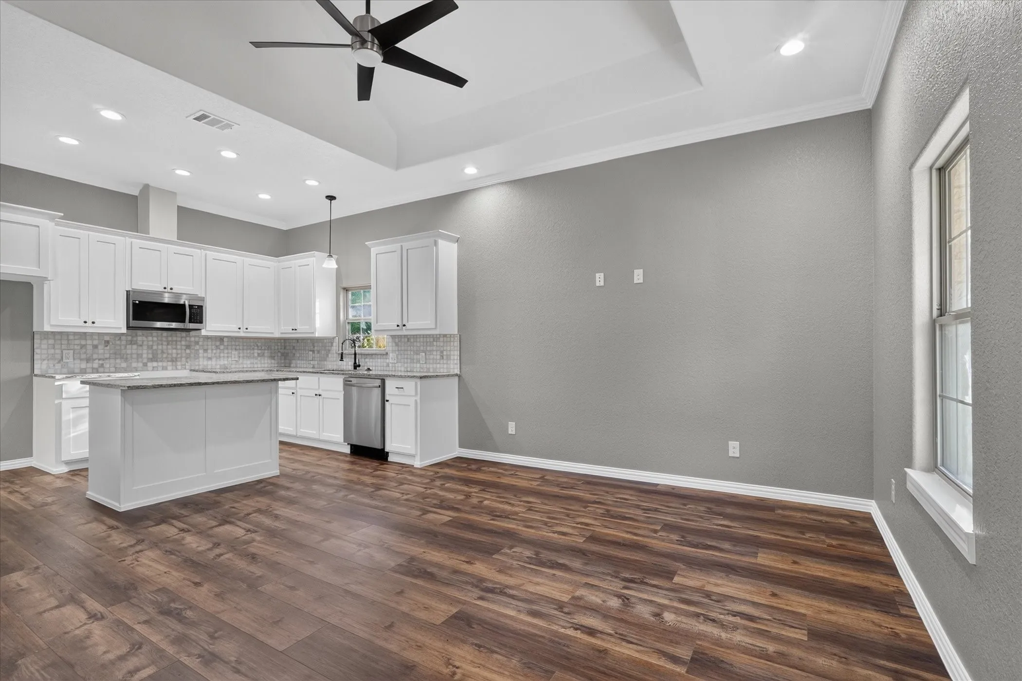 Kitchen featuring white cabinetry, stainless steel appliances, a center island, tile backsplash, and wood-finish flooring