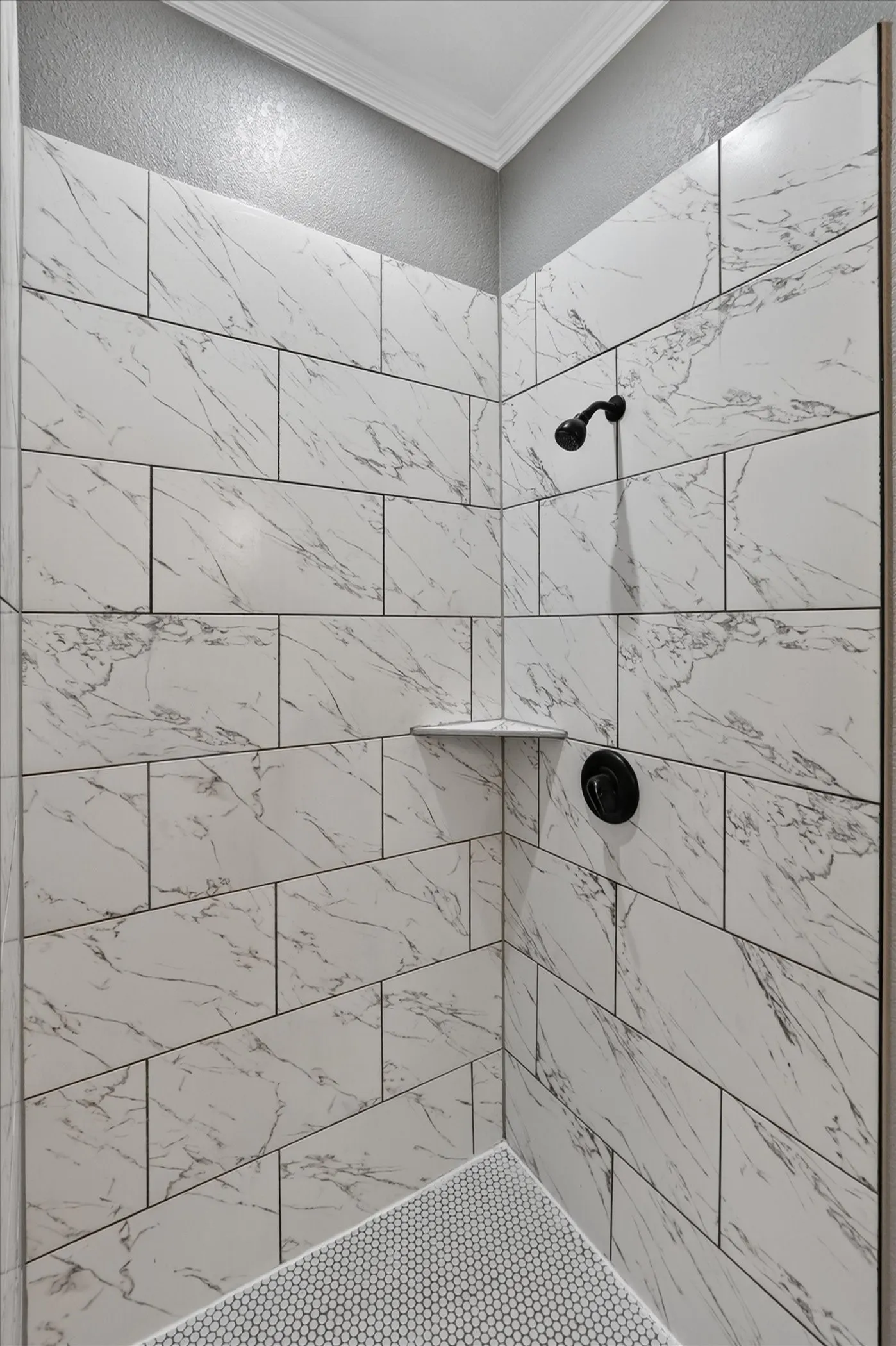 Shower stall with white rectangular tile walls, corner shelving, and matte black fixtures