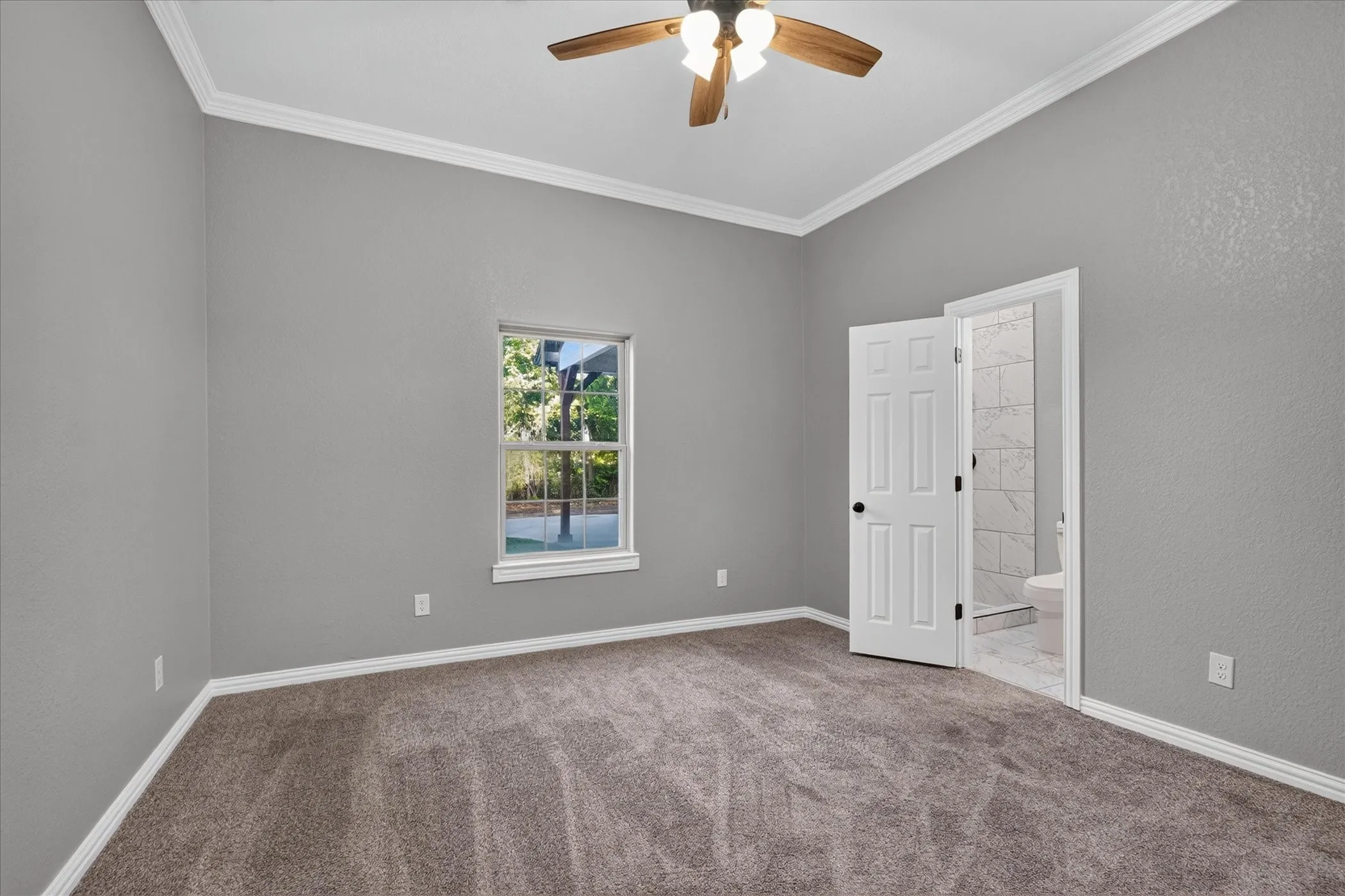 Carpeted room with a vaulted ceiling, ceiling fan, and crown molding