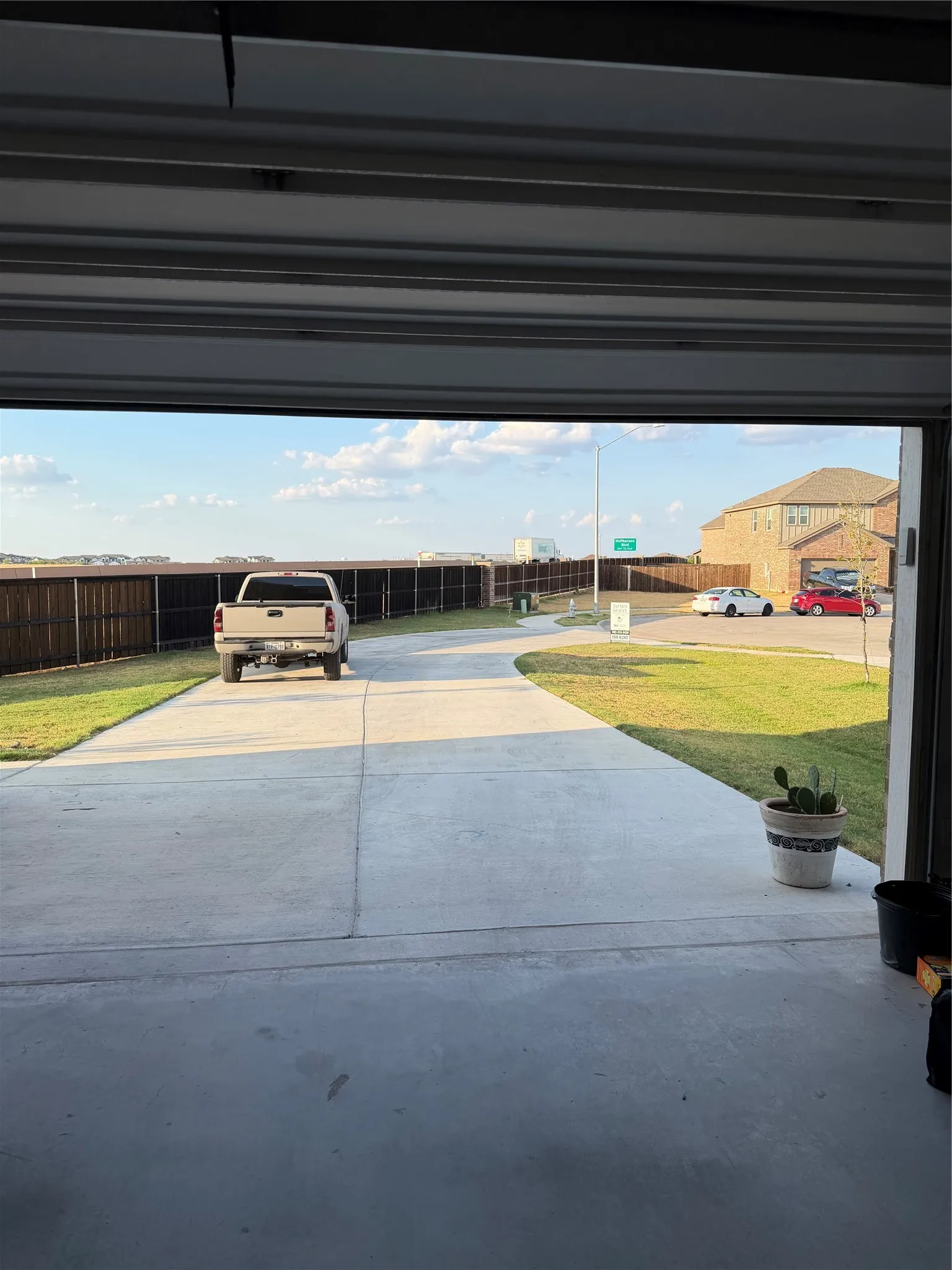 Paved driveway leading to a residential street with a partial brick-clad structure visible