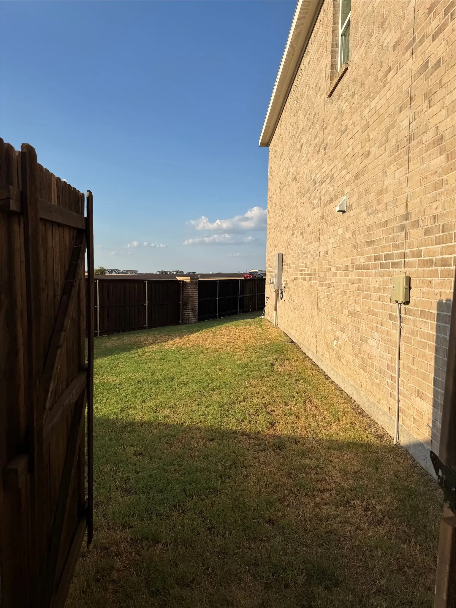 Brick exterior with a side yard, wood fencing, and a window opening
