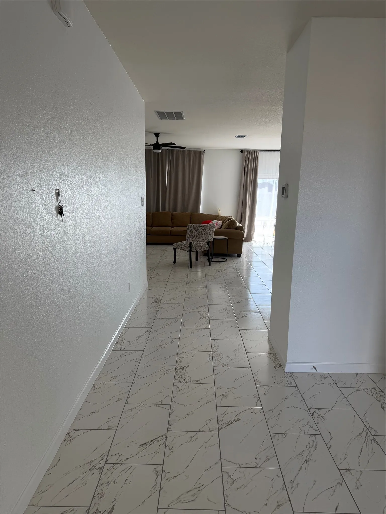 Marble-look floor tile, white walls, and a ceiling fan with light fixture