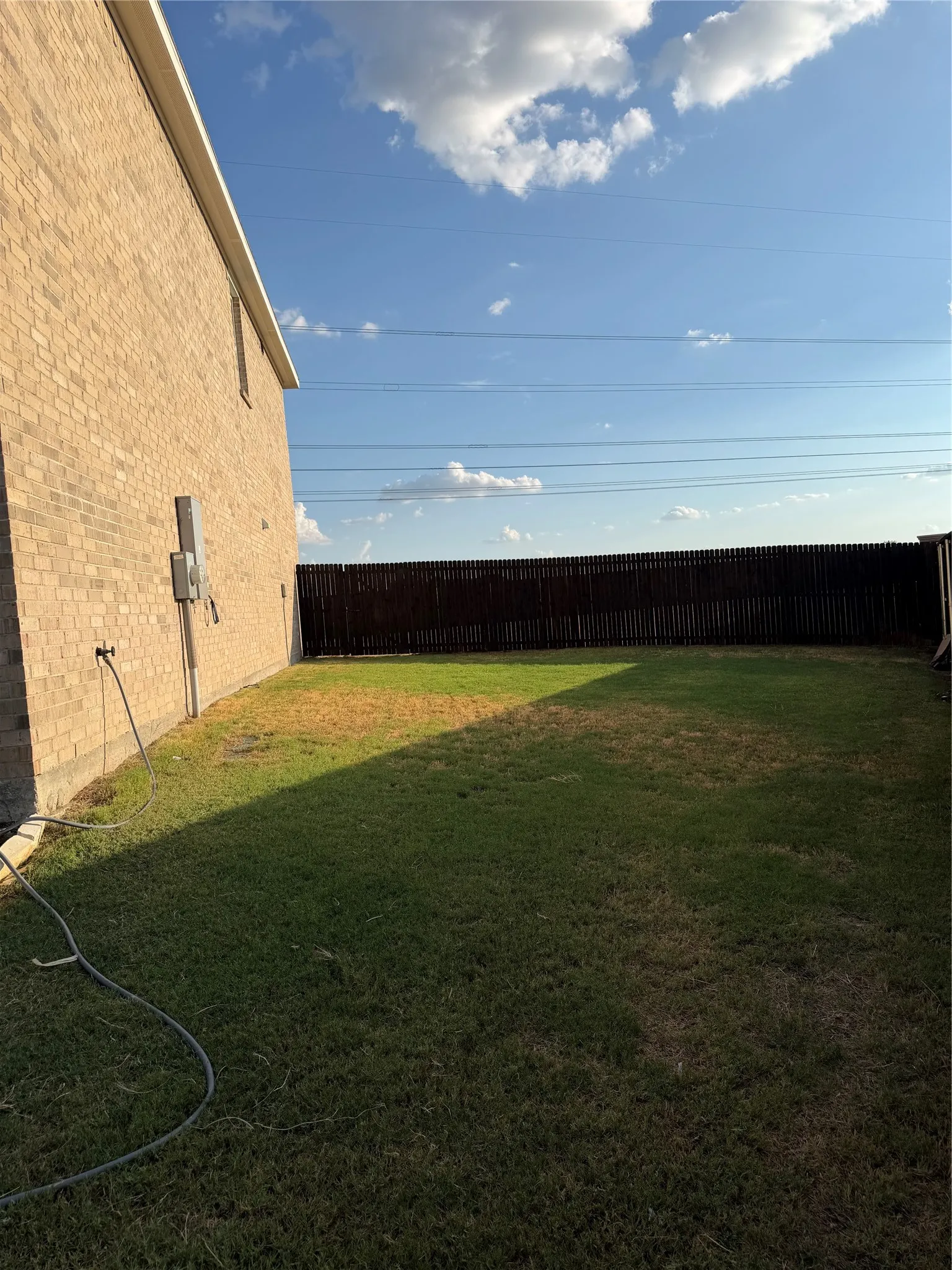 Expansive grassy area with a privacy fence