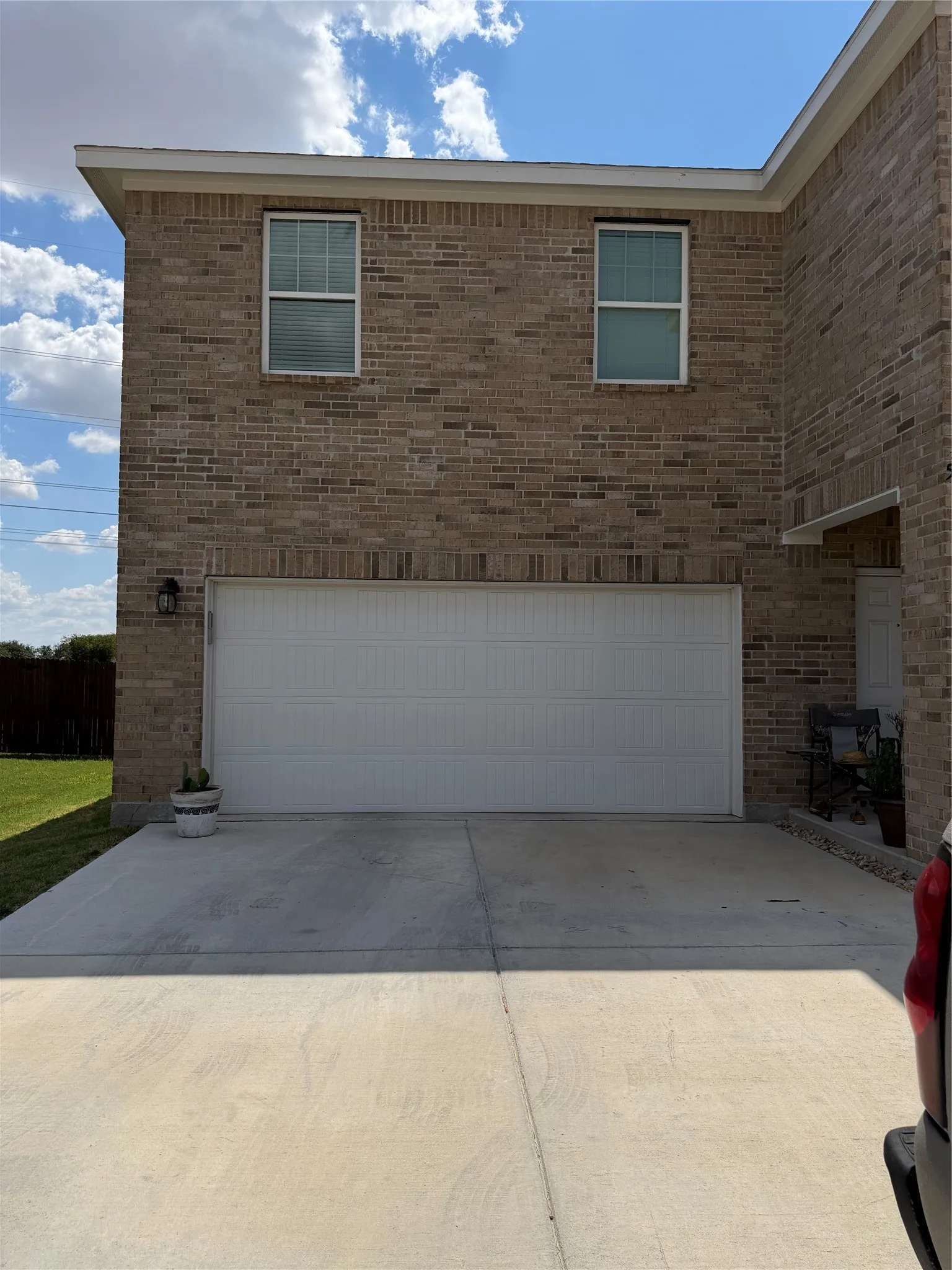 Brick exterior with dual windows, an attached garage, and a concrete driveway